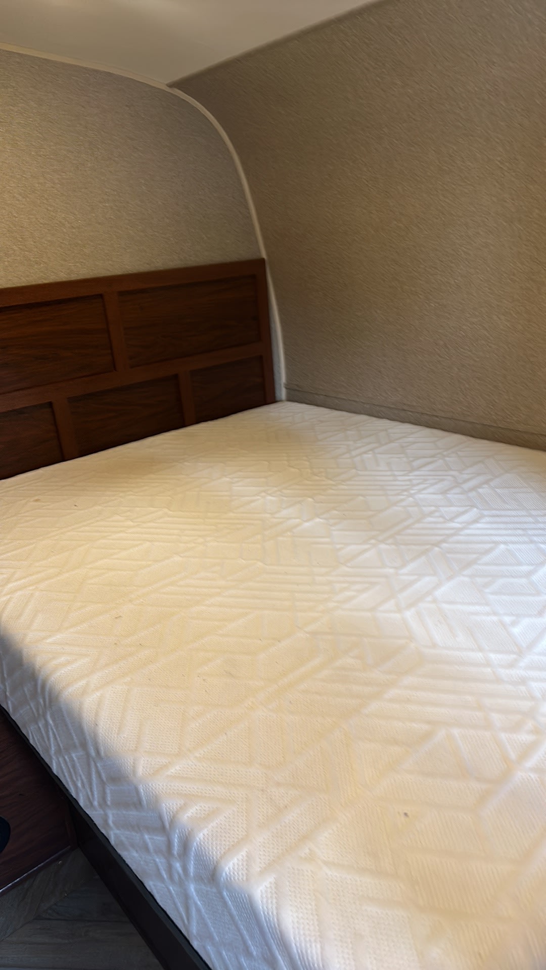 Cozy RV rental bedroom with wooden headboard and white patterned mattress, offering a comfortable sleeping space.. Forest River Vengeance Toy Hauler 2016