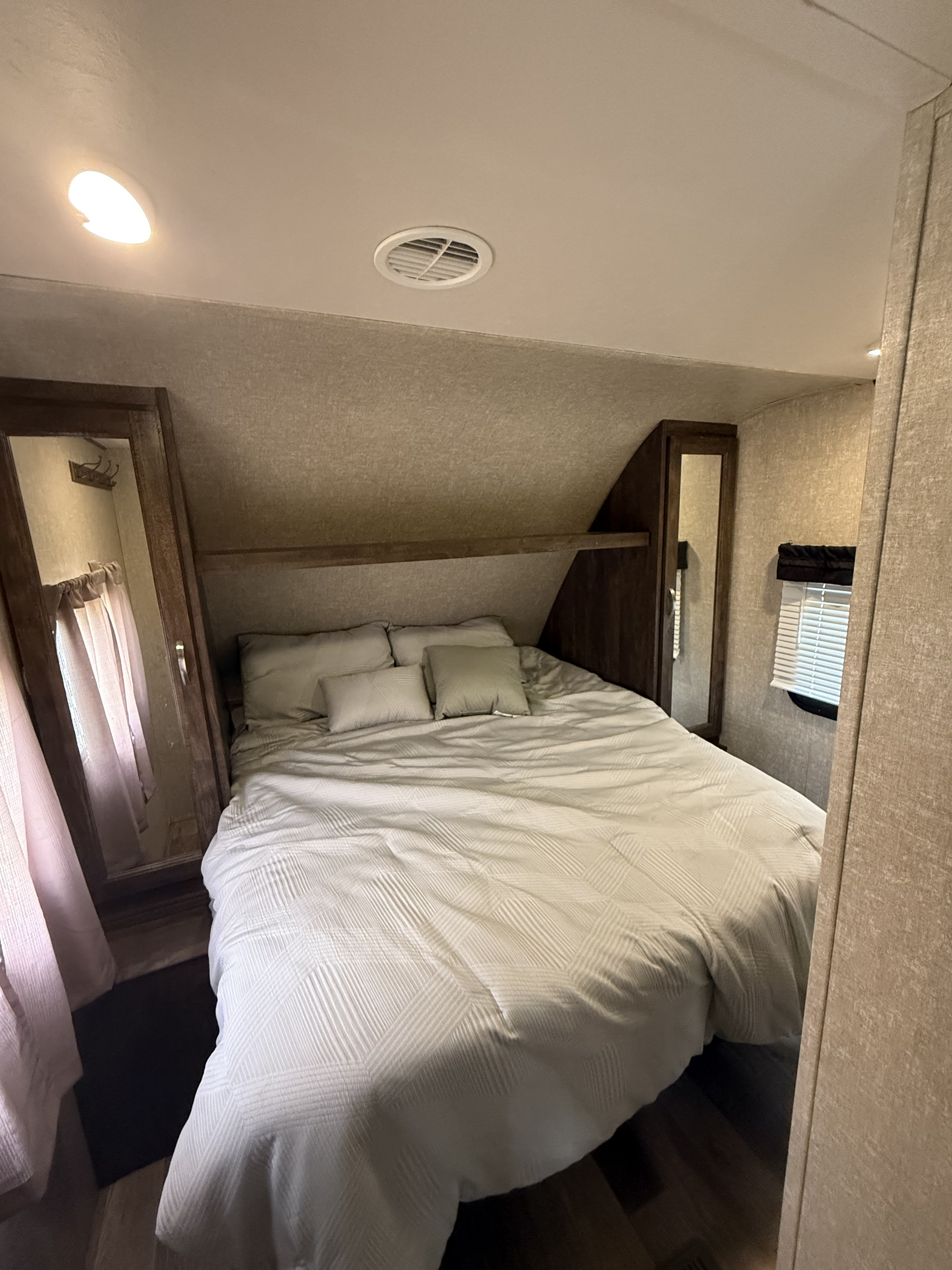 Cozy RV rental bedroom features a queen bed, mirrored wardrobes, overhead shelf, and window for comfortable travel.. Forest River Vibe Extreme Lite 2017