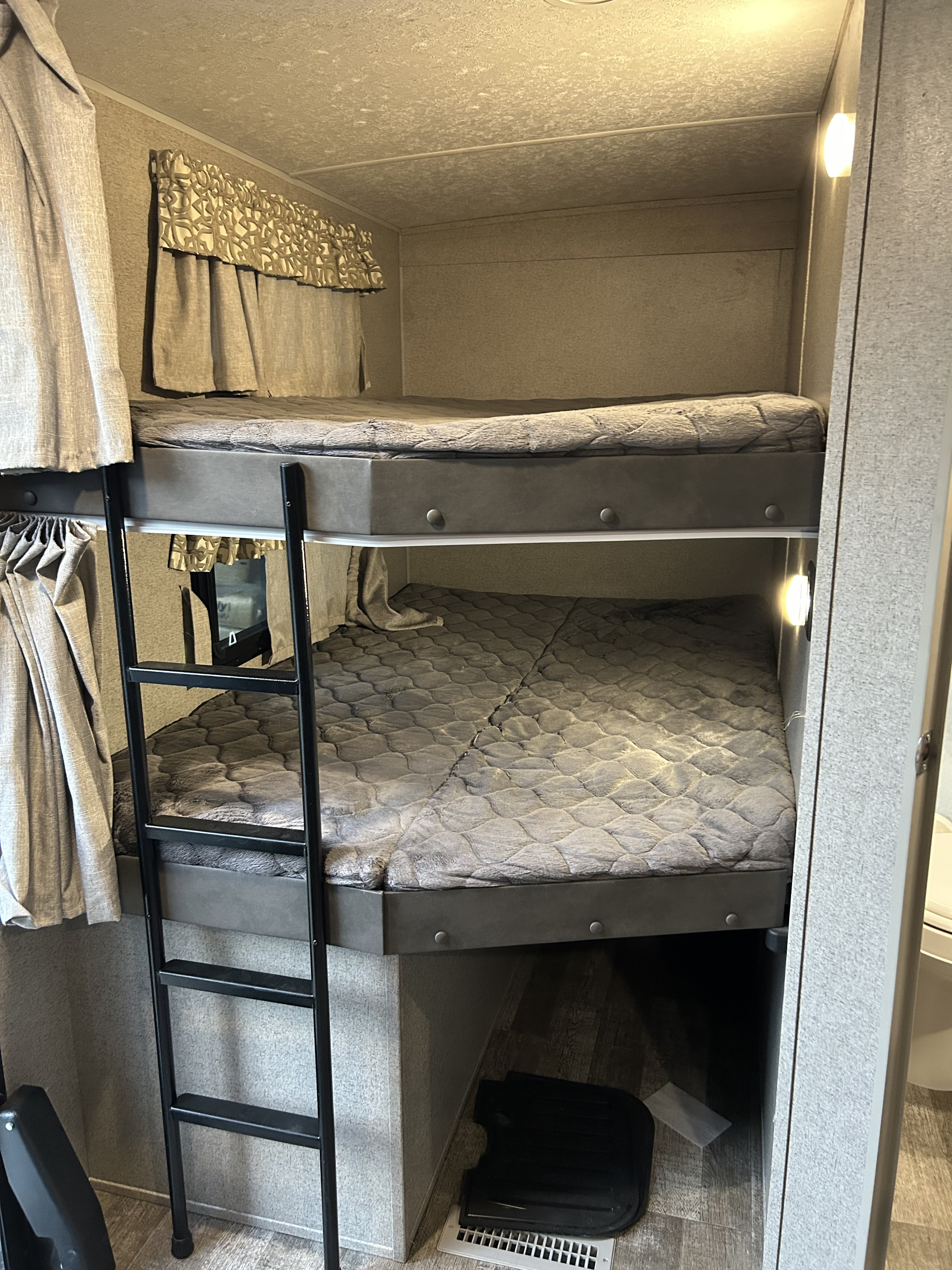 View of RV rental bunk beds, featuring a ladder, soft quilted mattresses, and individual lighting for comfortable sleeping.. Forest River Rockwood Ultra Lite 2022