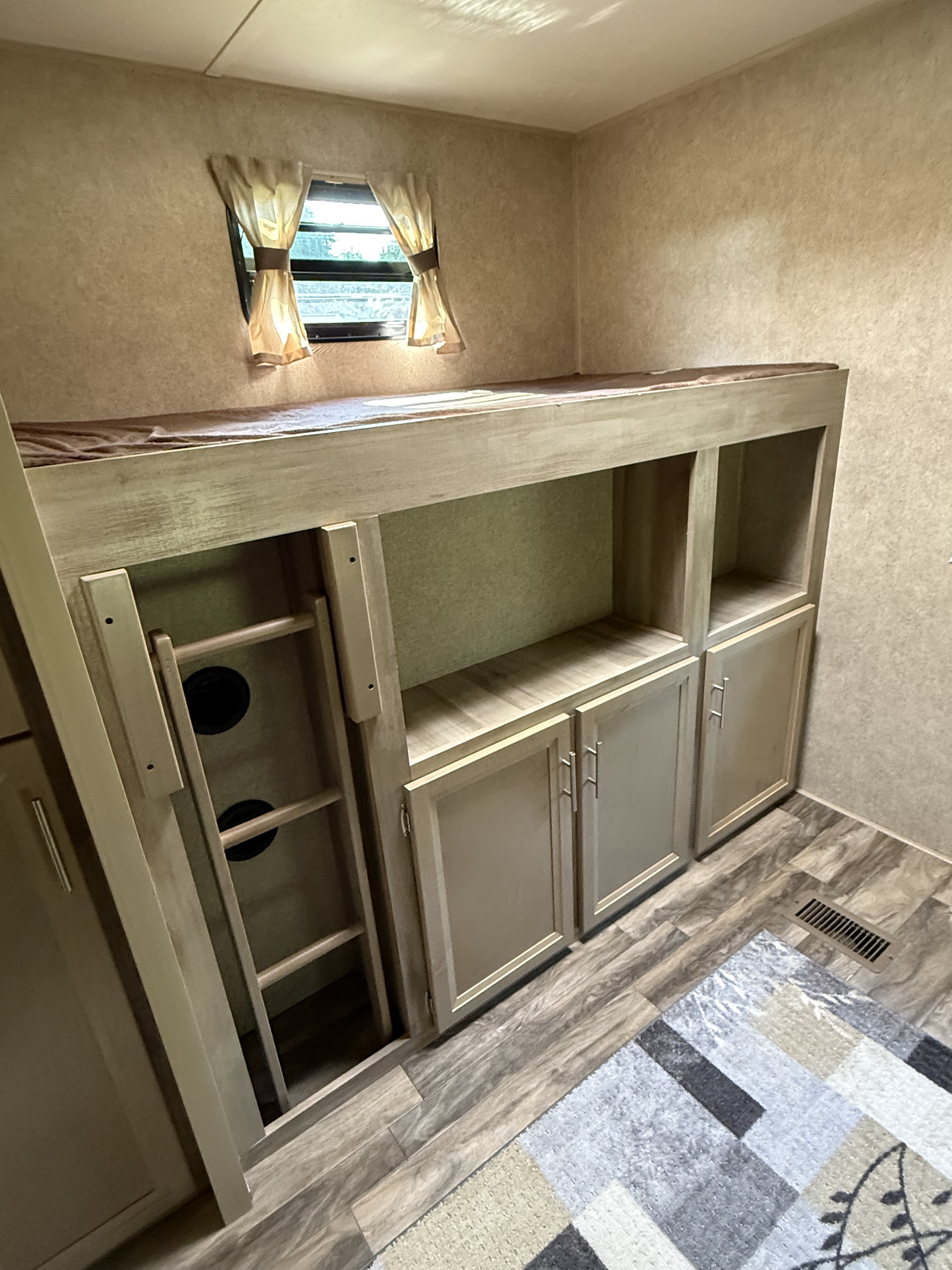 Cozy RV rental interior with bunk beds, ladder, built-in storage, and a window with curtains.. Coachmen Catalina 2020