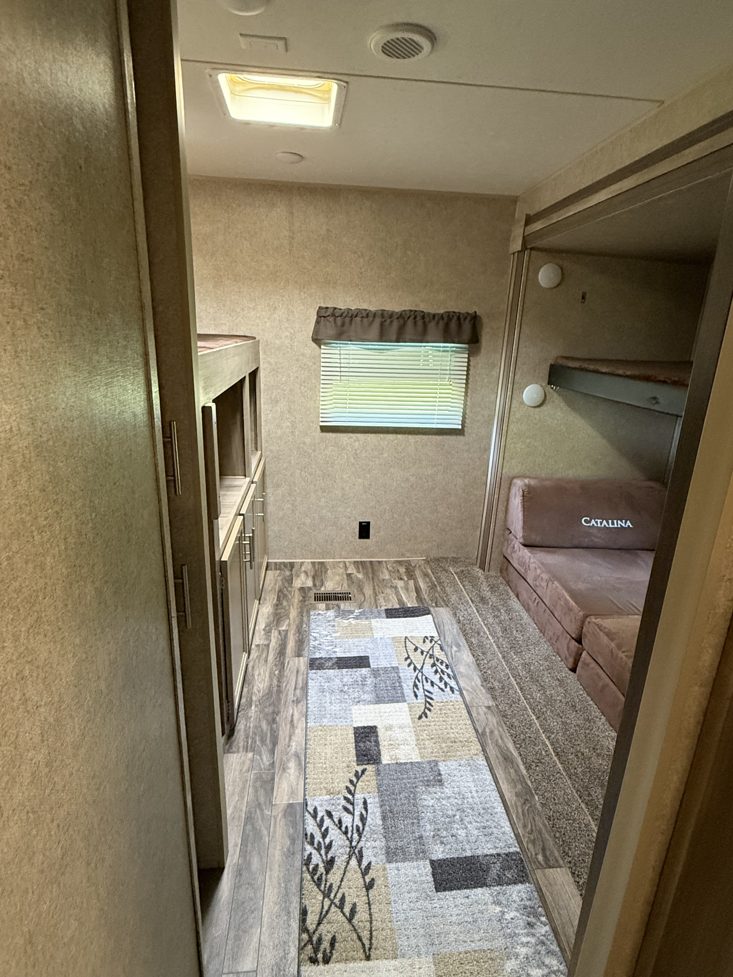 RV rental with cozy bunk beds, wood-look floor, patterned rug, and a convertible "Catalina" sofa bed. Ideal for travel.. Coachmen Catalina 2020