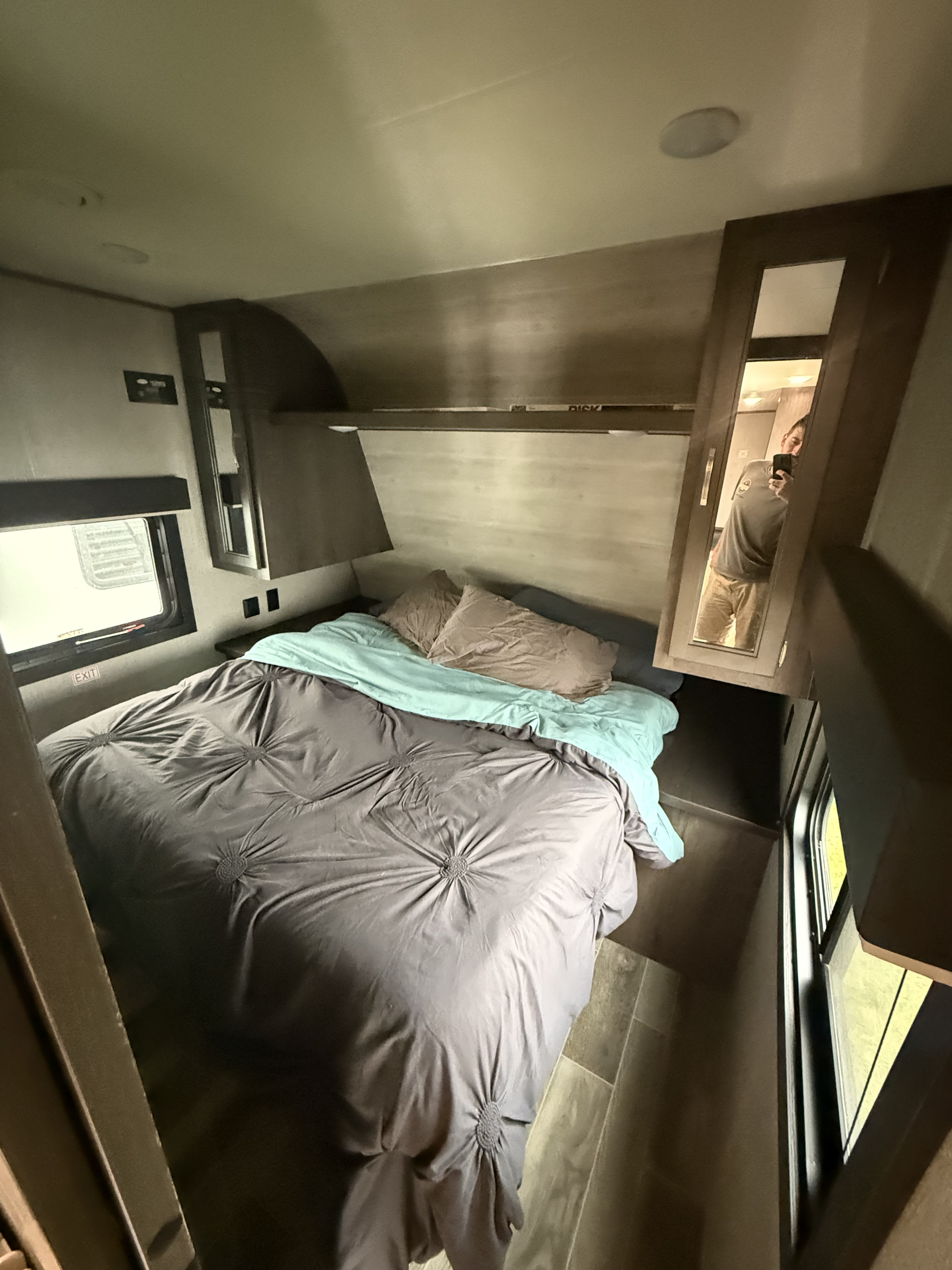 Comfortable RV rental bedroom: A grey bed with soft bedding, overhead storage, and an emergency exit window. Compact and functional.. Jayco Jay Flight SLX 2021