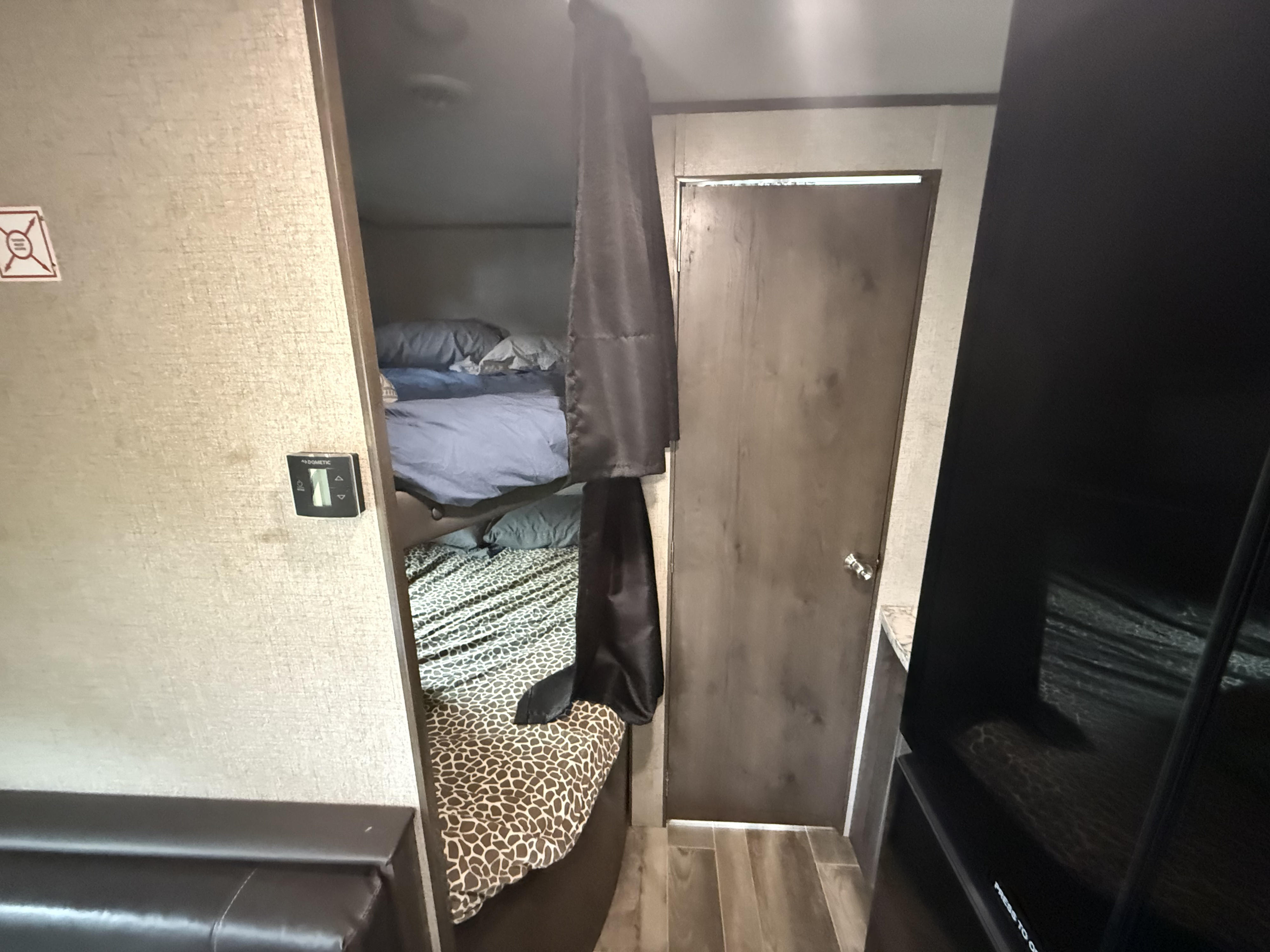 RV rental interior featuring bunk beds, a Dometic thermostat, and a wooden door. Ideal compact living space.. Jayco Jay Flight SLX 2021
