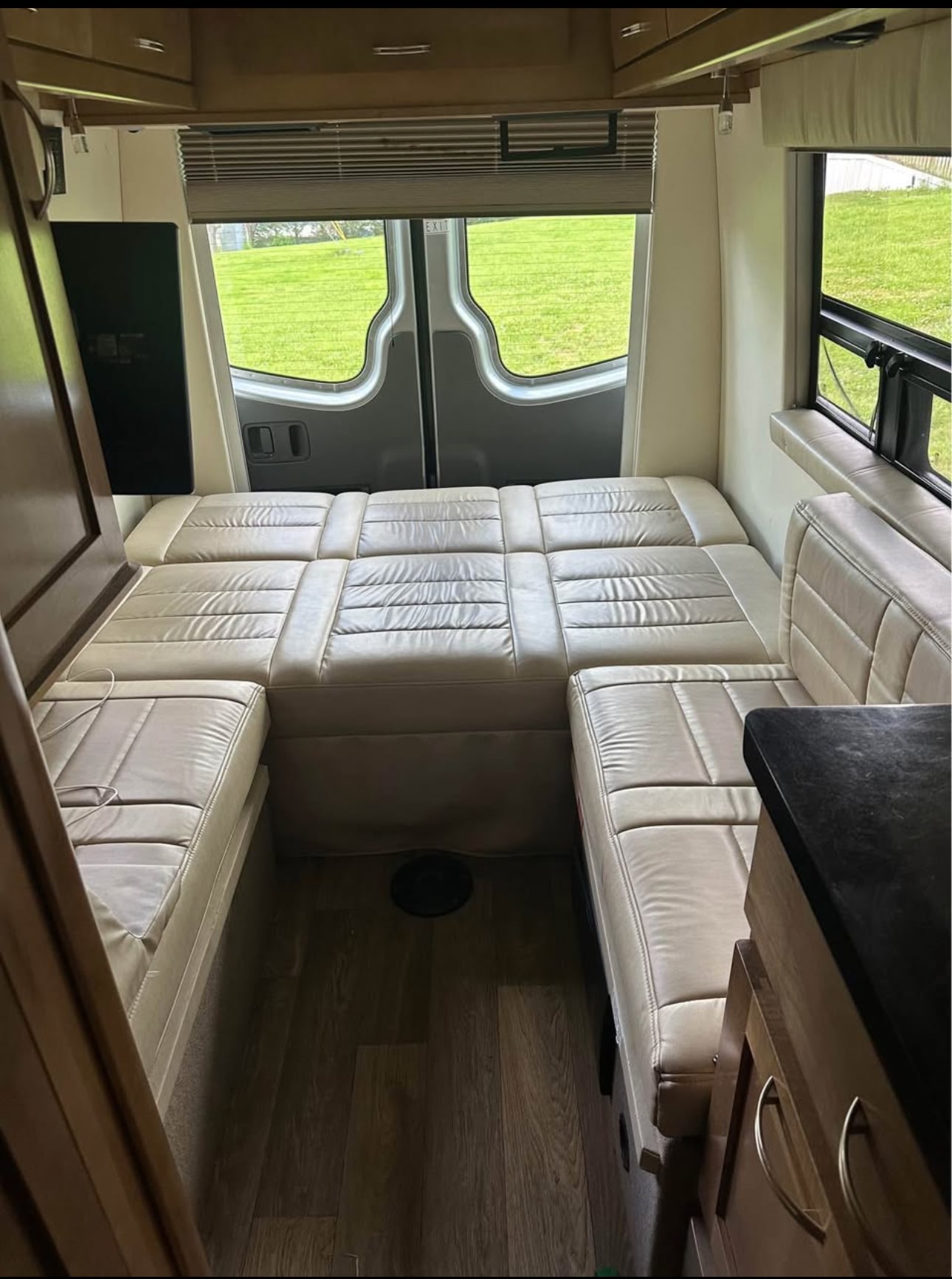 Experience an RV rental! Rear interior of a camper van with plush, light-colored modular seating/bed, wood floor, and large windows.. Coachmen Galleria 2018