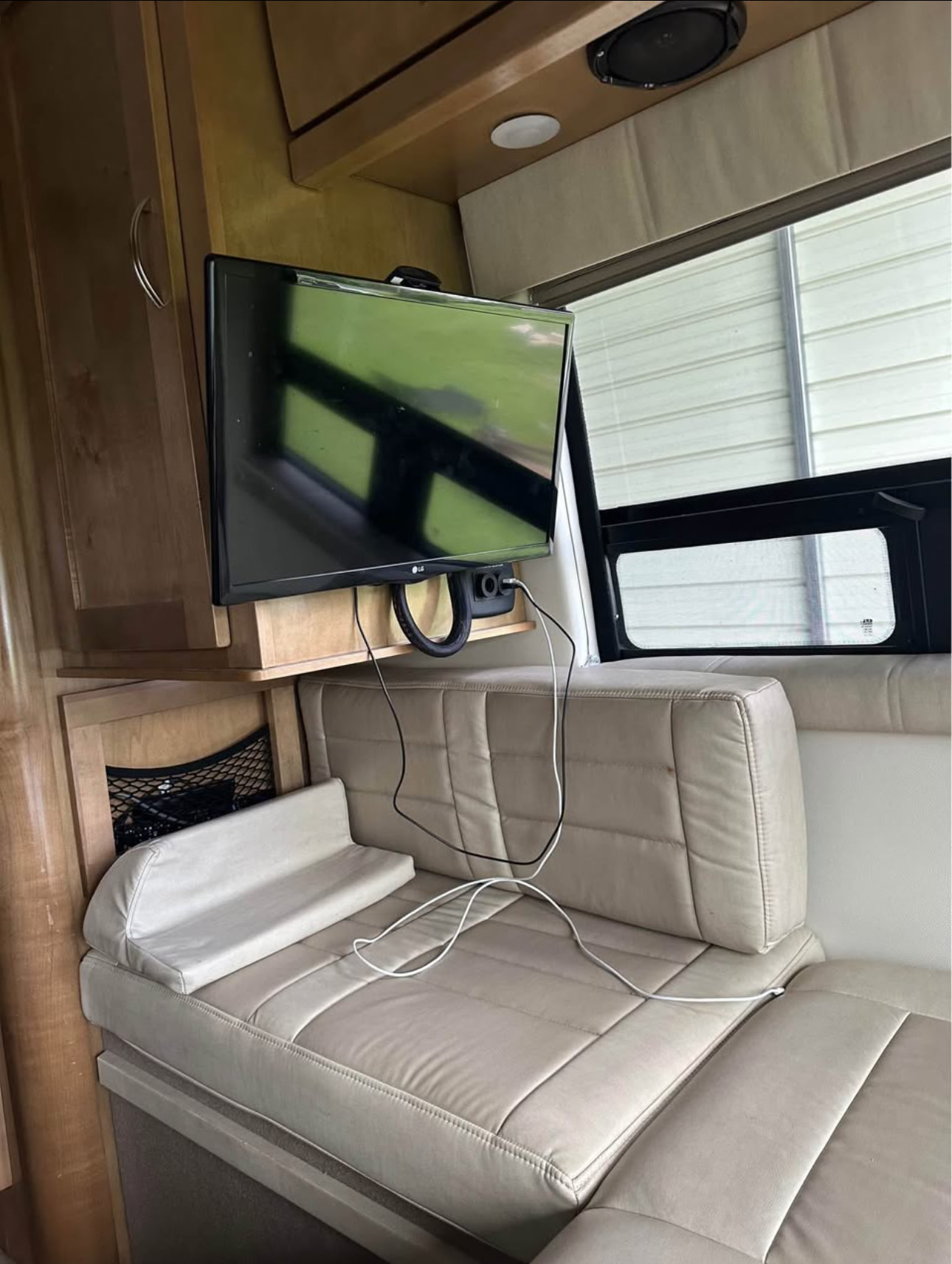 RV rental: Interior of a compact lounge area with a mounted TV, light-colored bench seating, and wooden cabinets.. Coachmen Galleria 2018
