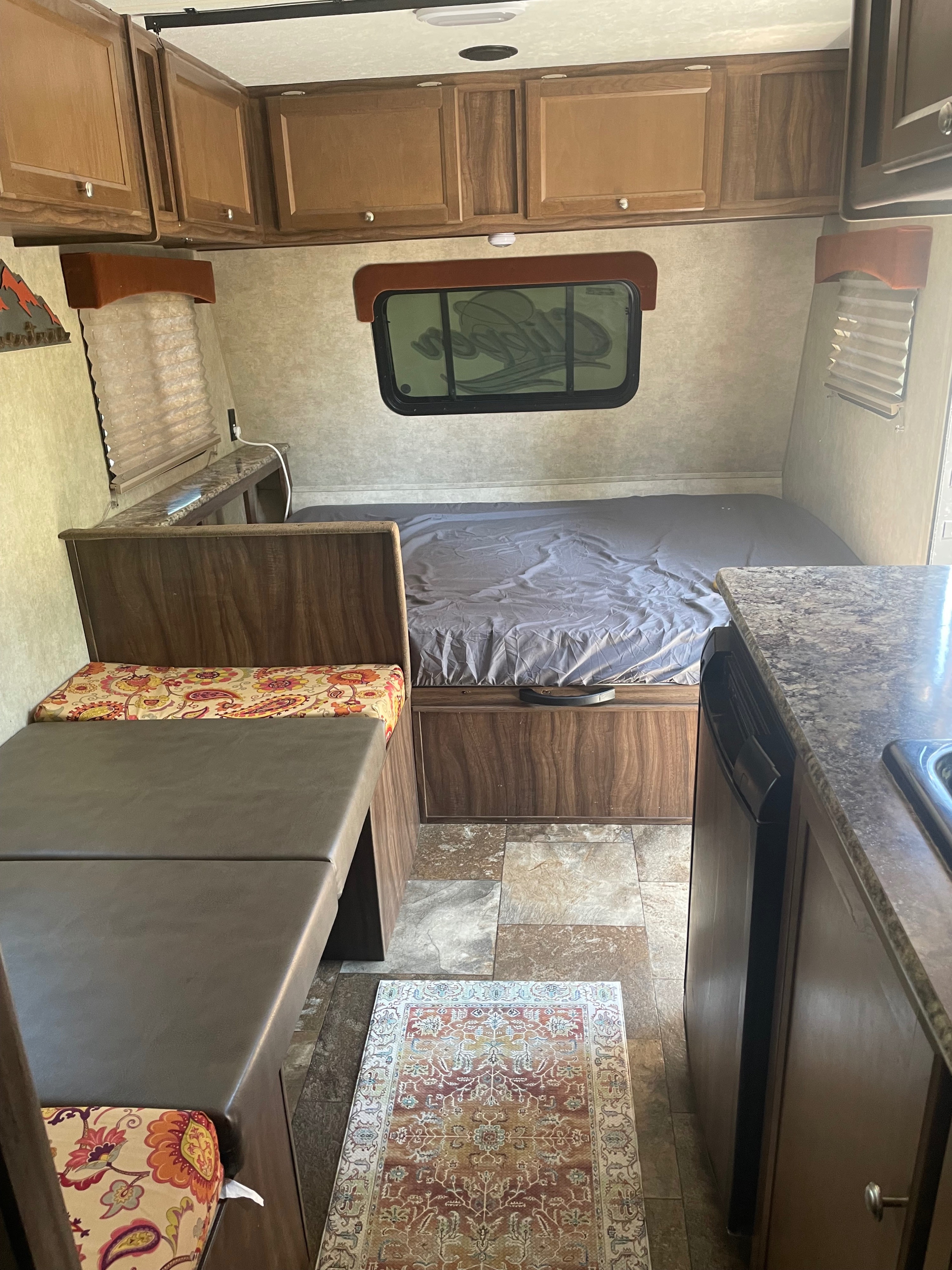 Cozy RV rental interior: features a bed, dinette with patterned cushions, overhead cabinets, and a compact kitchen.. Forest River 2017 forest river clipper towable 17bh 2017