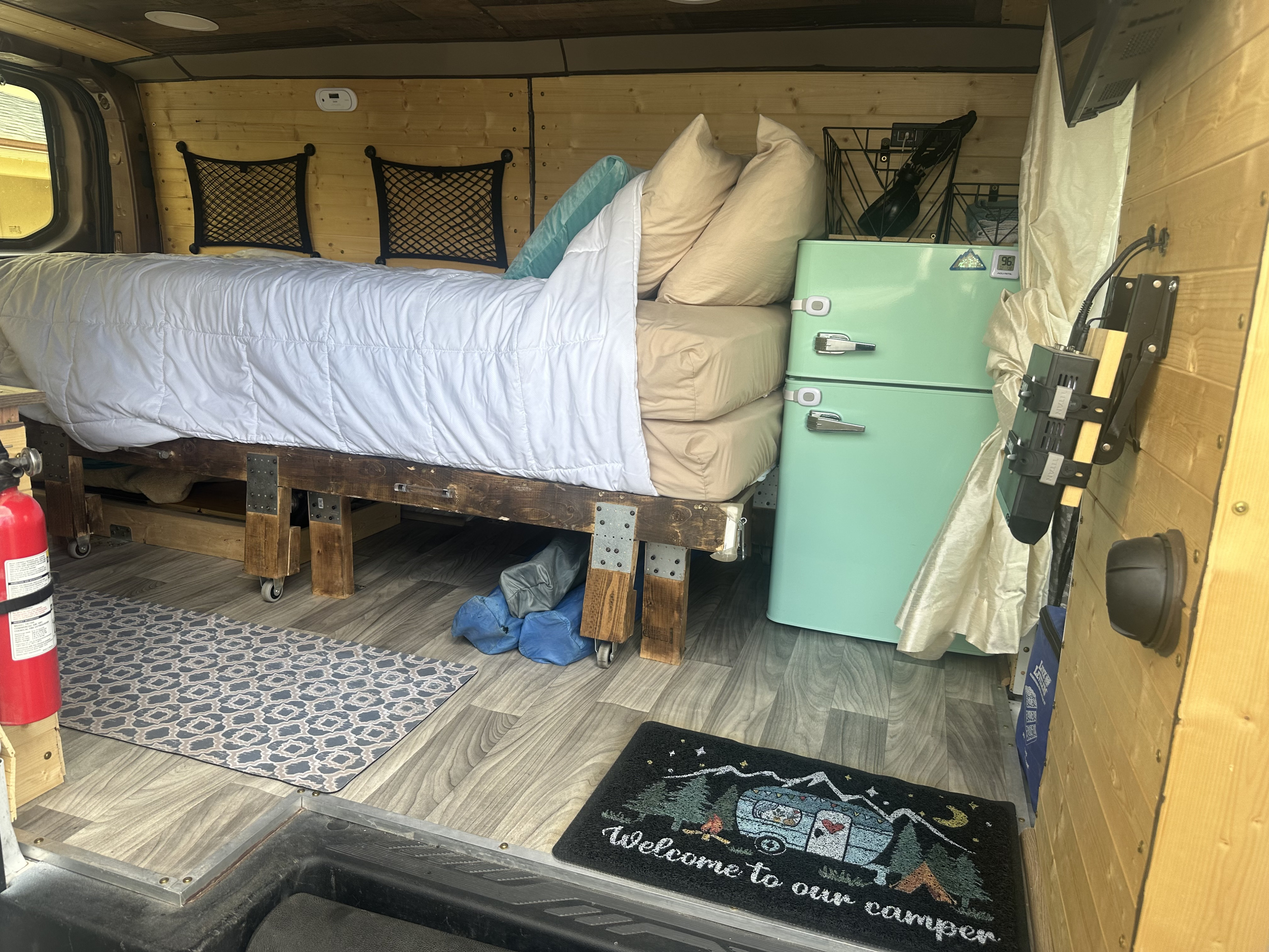 Inside a comfortable RV rental: a custom campervan interior with bed, retro fridge, and smart under-bed storage.. FORD TRANSIT 250 2015