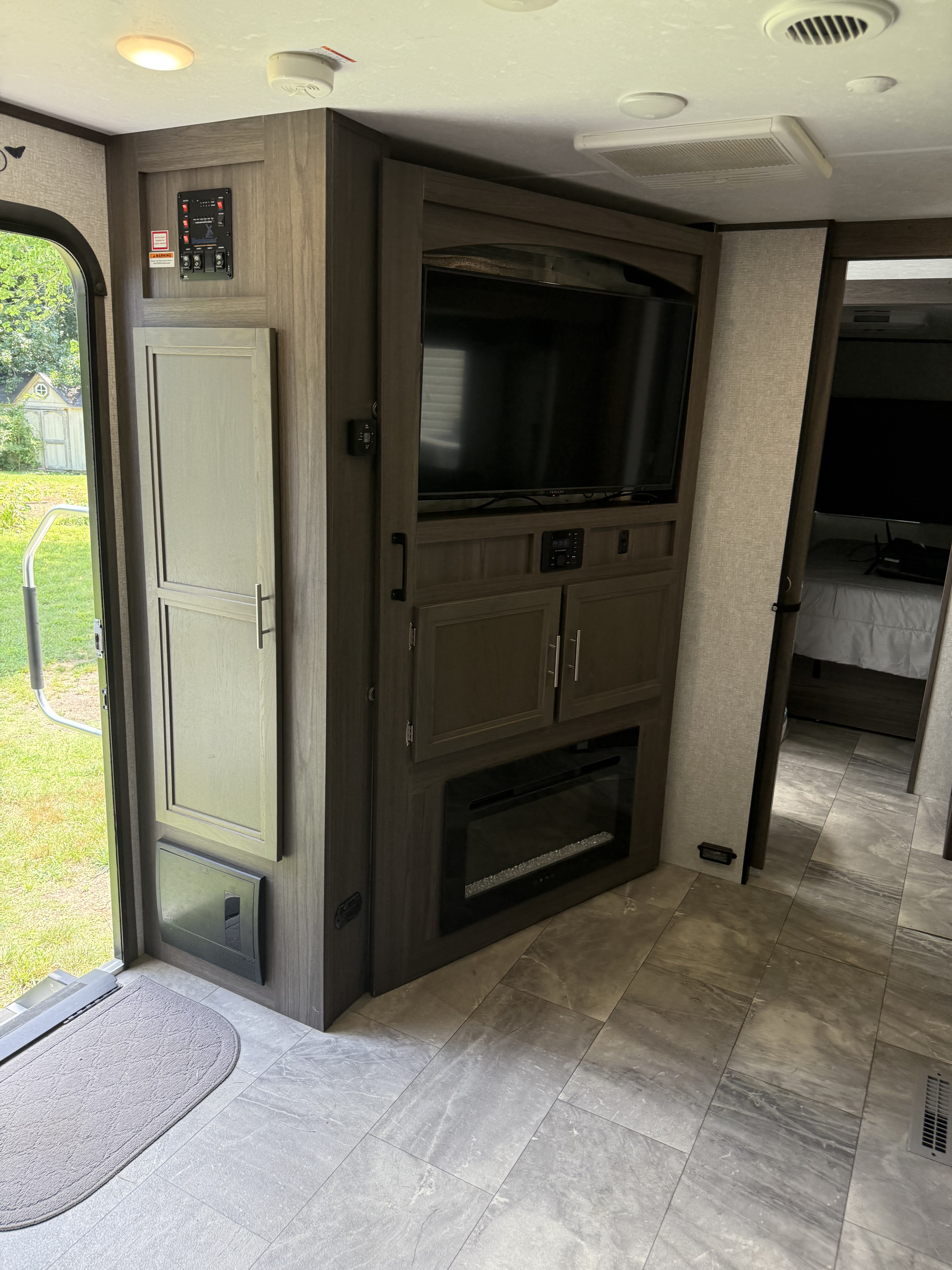 Explore comfort in your RV rental! This modern camper interior features a control panel, entertainment unit with TV & fireplace, and a cozy bedroom.. Dutchmen Kodiak Ultimate 2021