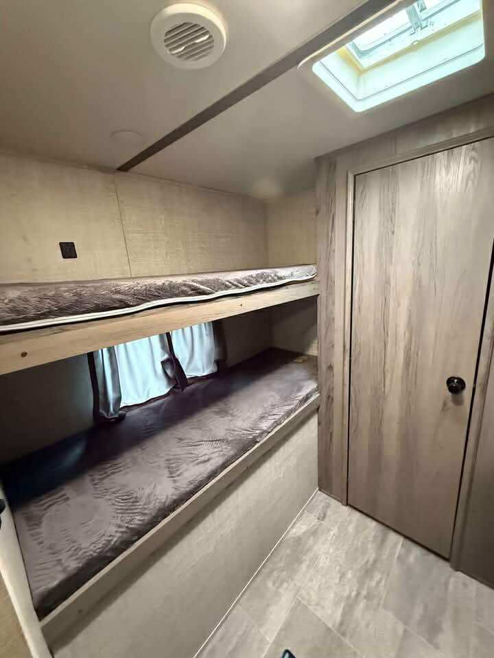 RV rental: two sturdy bunk beds with mattresses, a ceiling skylight, and a closet. Efficient and cozy interior for travel.. Gulf Stream Kingsport Supreme 2020