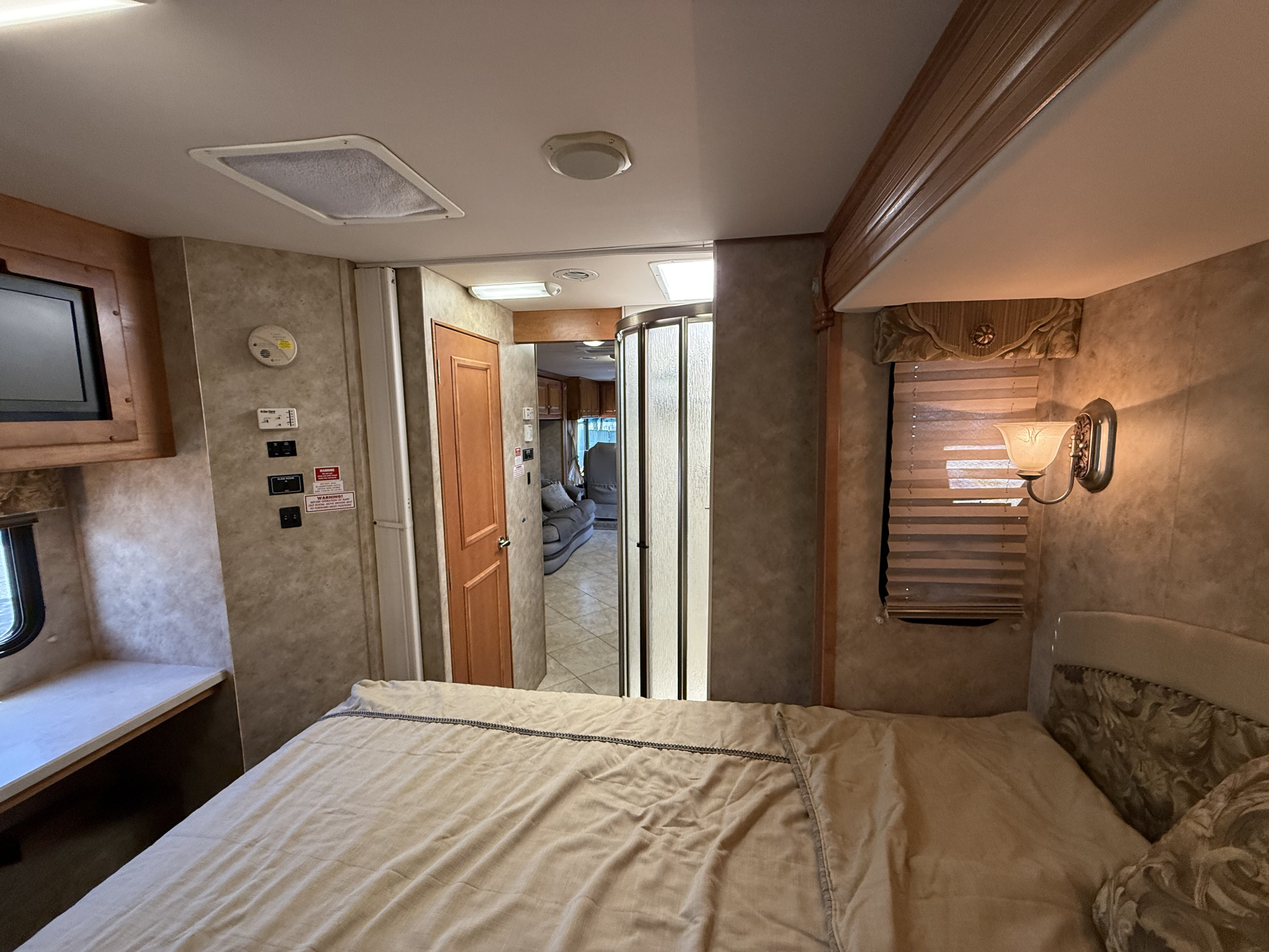 Interior of an RV rental: a cozy bedroom featuring a comfortable bed, TV, and access to a shower and living area.. Gulf Stream Independence 2010