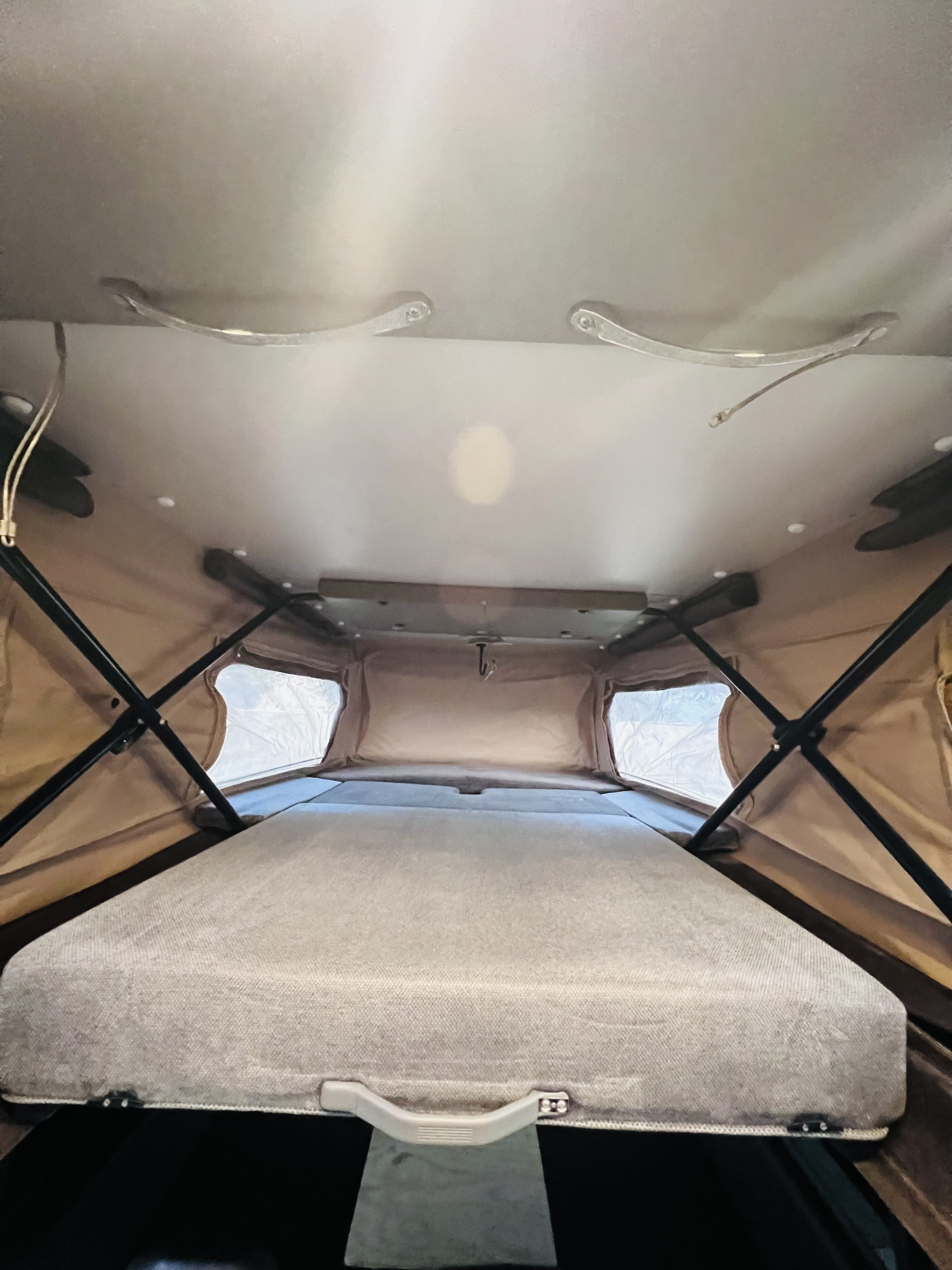 Inside an RV rental, this pop-up roof tent offers a cozy sleeping area with a bed and structural support.. Mercedes-Benz Sprinter 2015