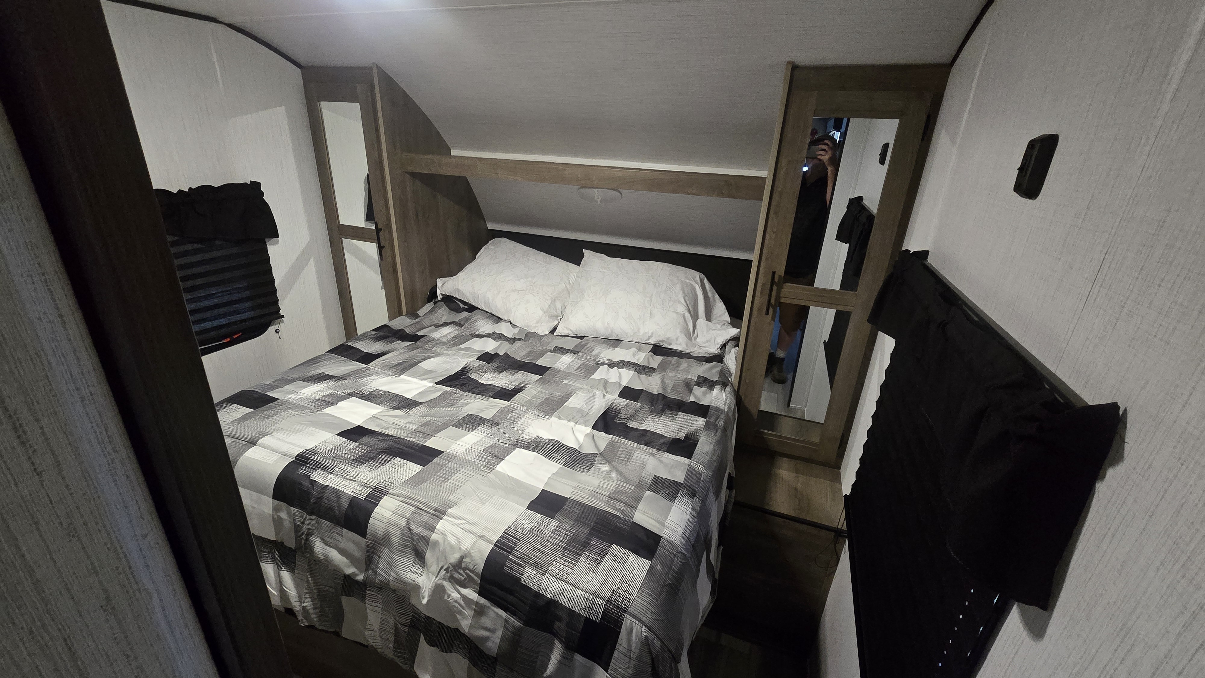 Comfortable RV rental bedroom featuring a checkered bed, white pillows, and practical storage, ready for travel.. Heartland RVs Pioneer 2022