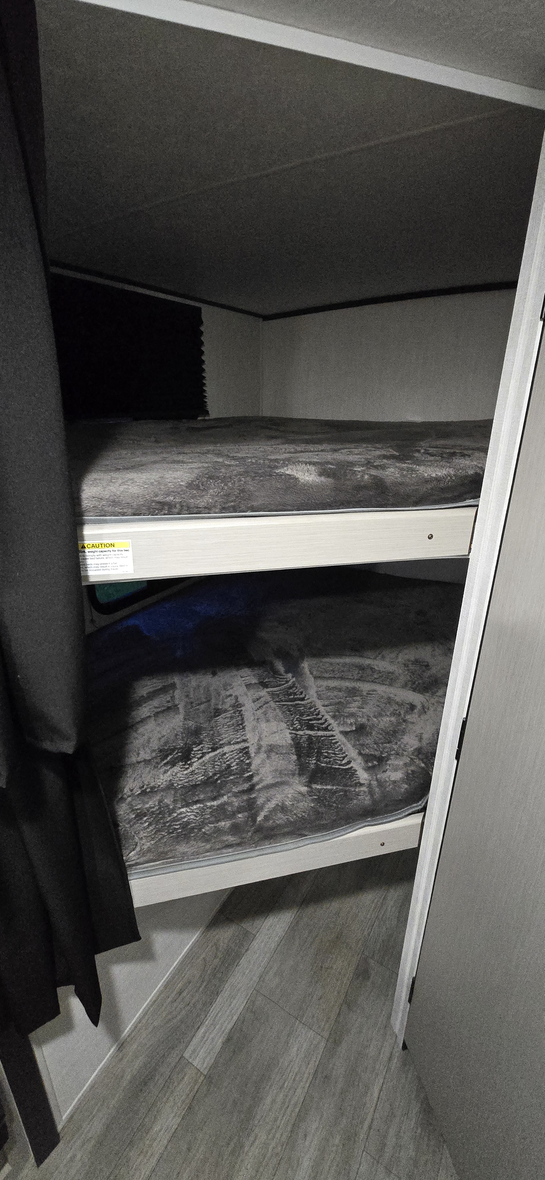Inside an RV rental: two compact bunk beds with grey bedding, offering a cozy sleeping area.. Coachmen Apex 2025