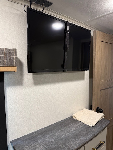 Inside an rv rental: a wall-mounted TV with safety strap, over a grey counter. Perfect for on-the-go entertainment and storage.. Dutchmen Dutchmen 2025