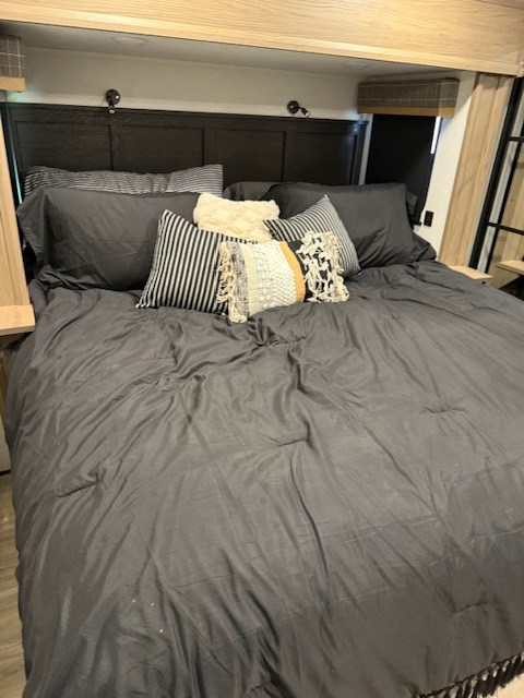 Spacious and cozy RV rental bedroom. Features a large bed with dark gray bedding and decorative pillows. Ideal for travelers.. Dutchmen Dutchmen 2025