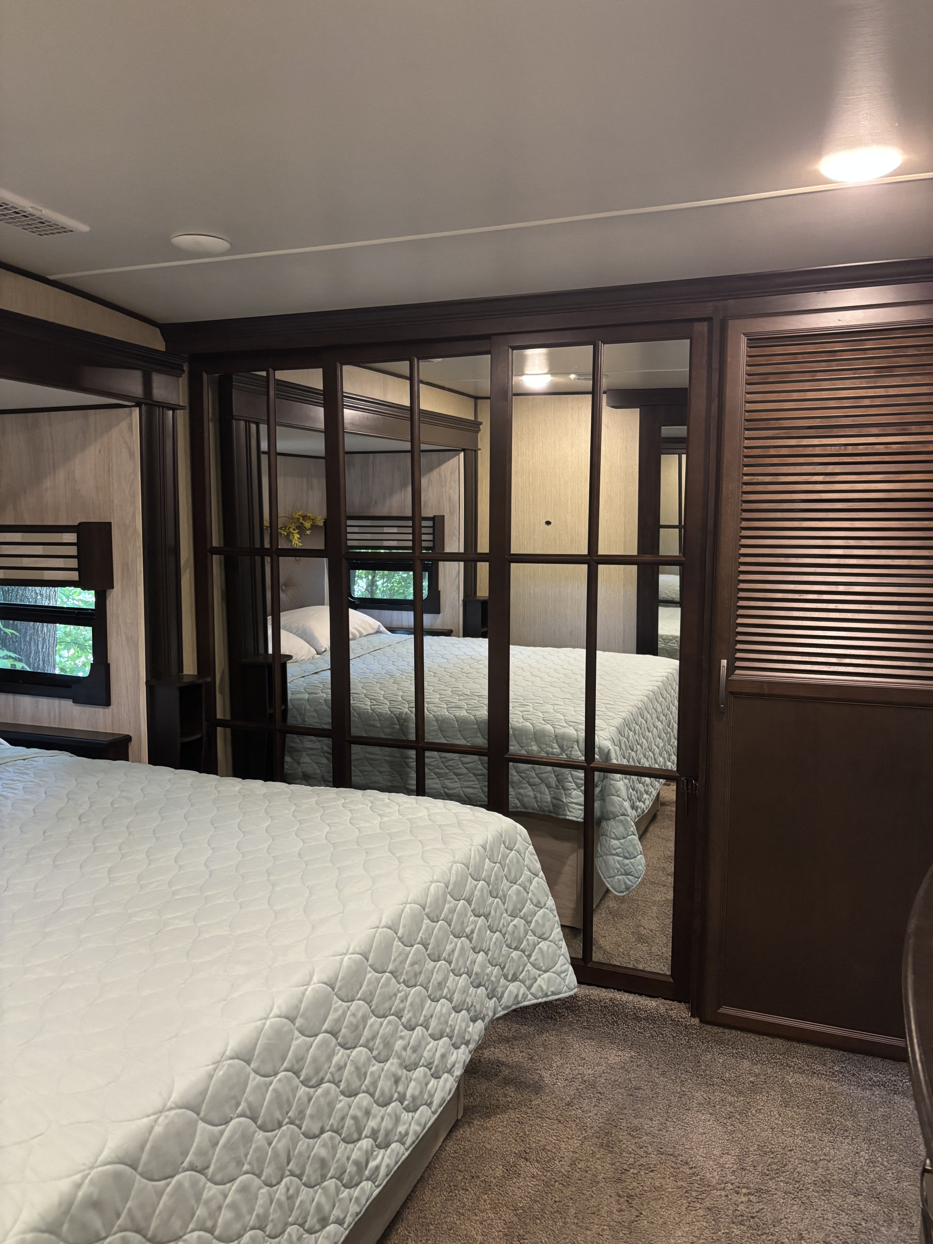 Spacious RV rental bedroom with quilted beds, reflective mirrored doors, and a bunk bed area, offering comfort.. 4x4fcmp23h6007284 Columbus 2017