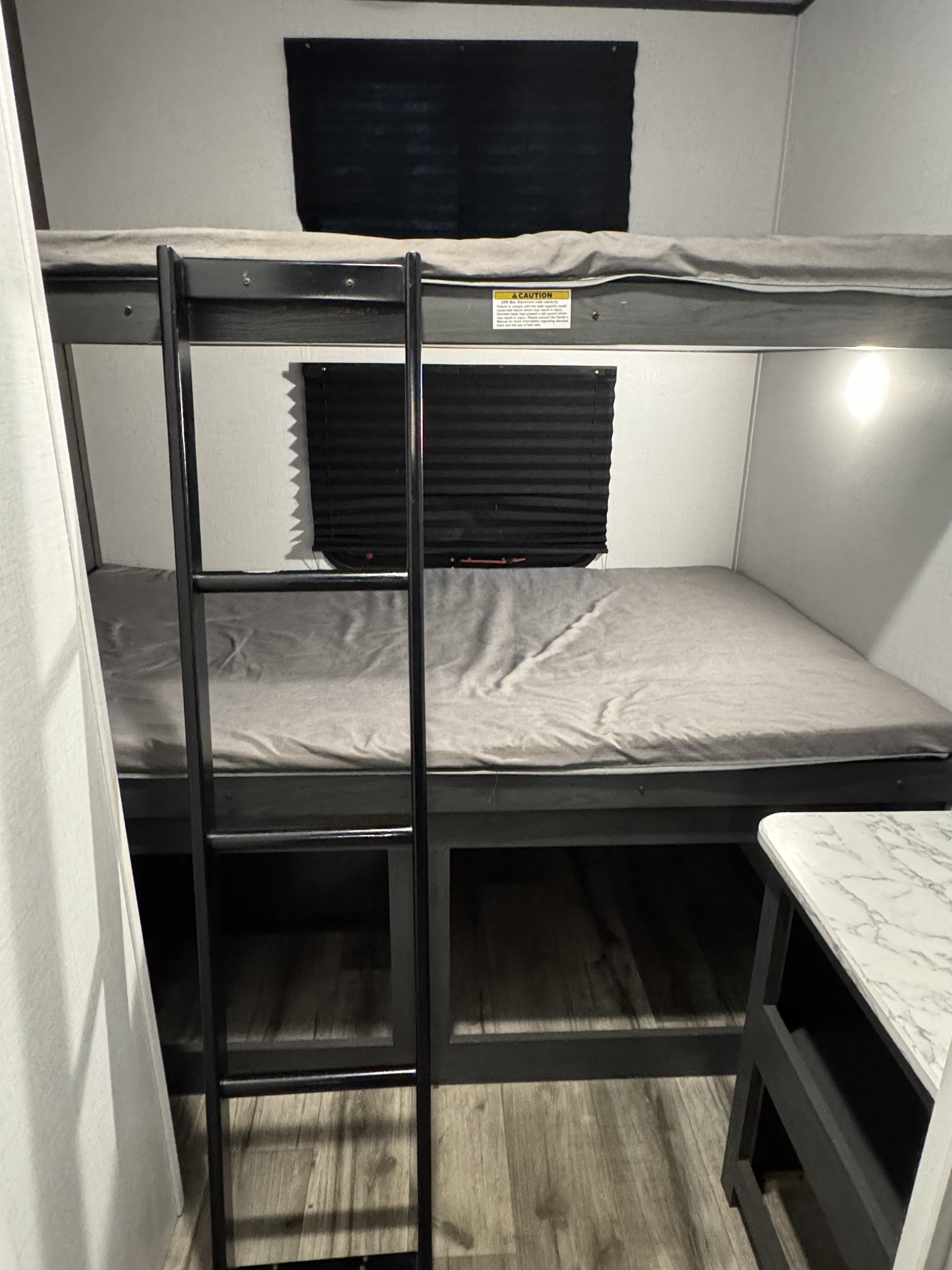 RV rental: a bunk bed sleeping area with a ladder, window blinds, and a bright light, perfect for family adventures.. Na Na 2025