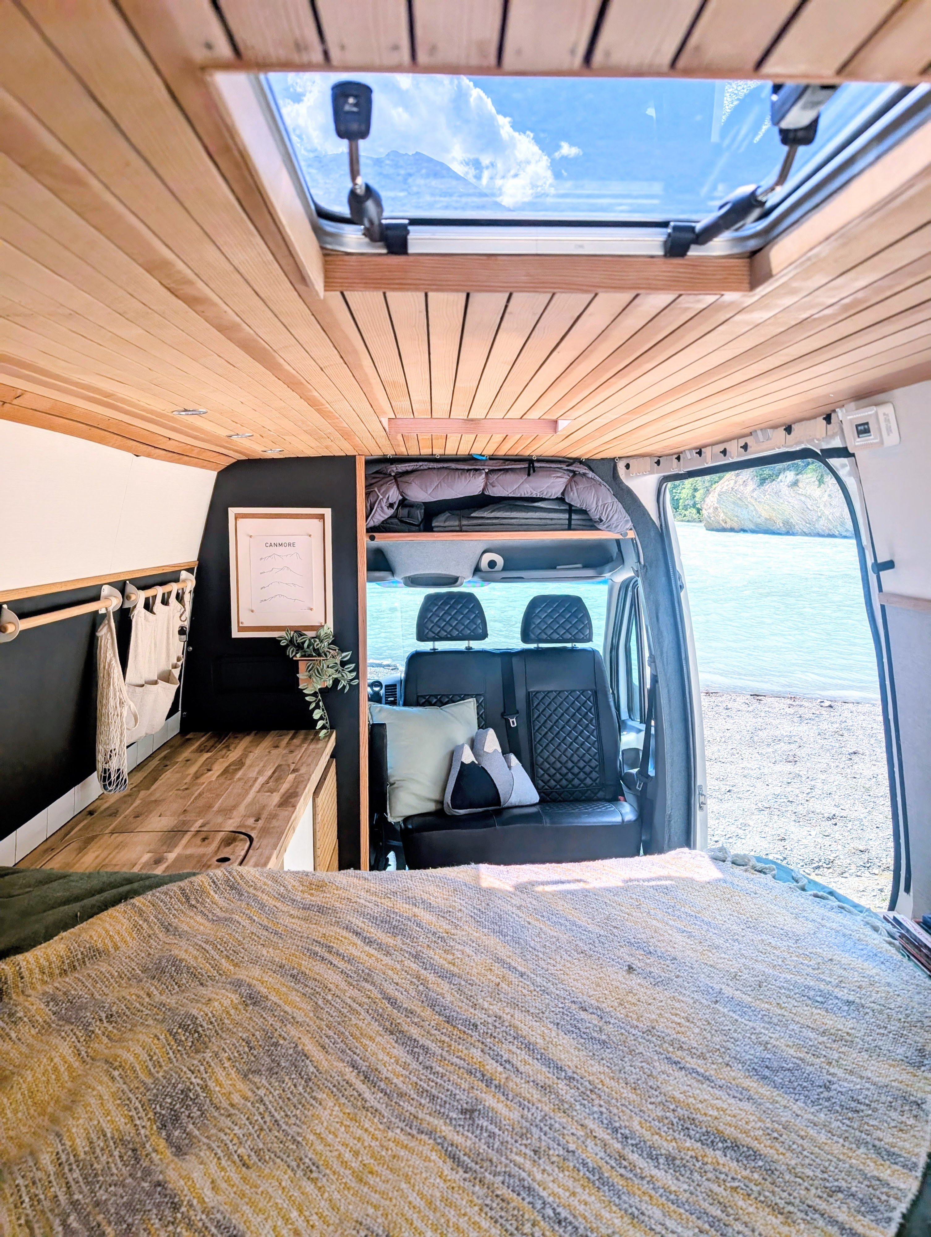 Cozy RV rental interior with wooden ceiling, skylight, and scenic water view, perfect for van life adventures.. Mercedes-Benz Mercedes Sprinter 2500 2015