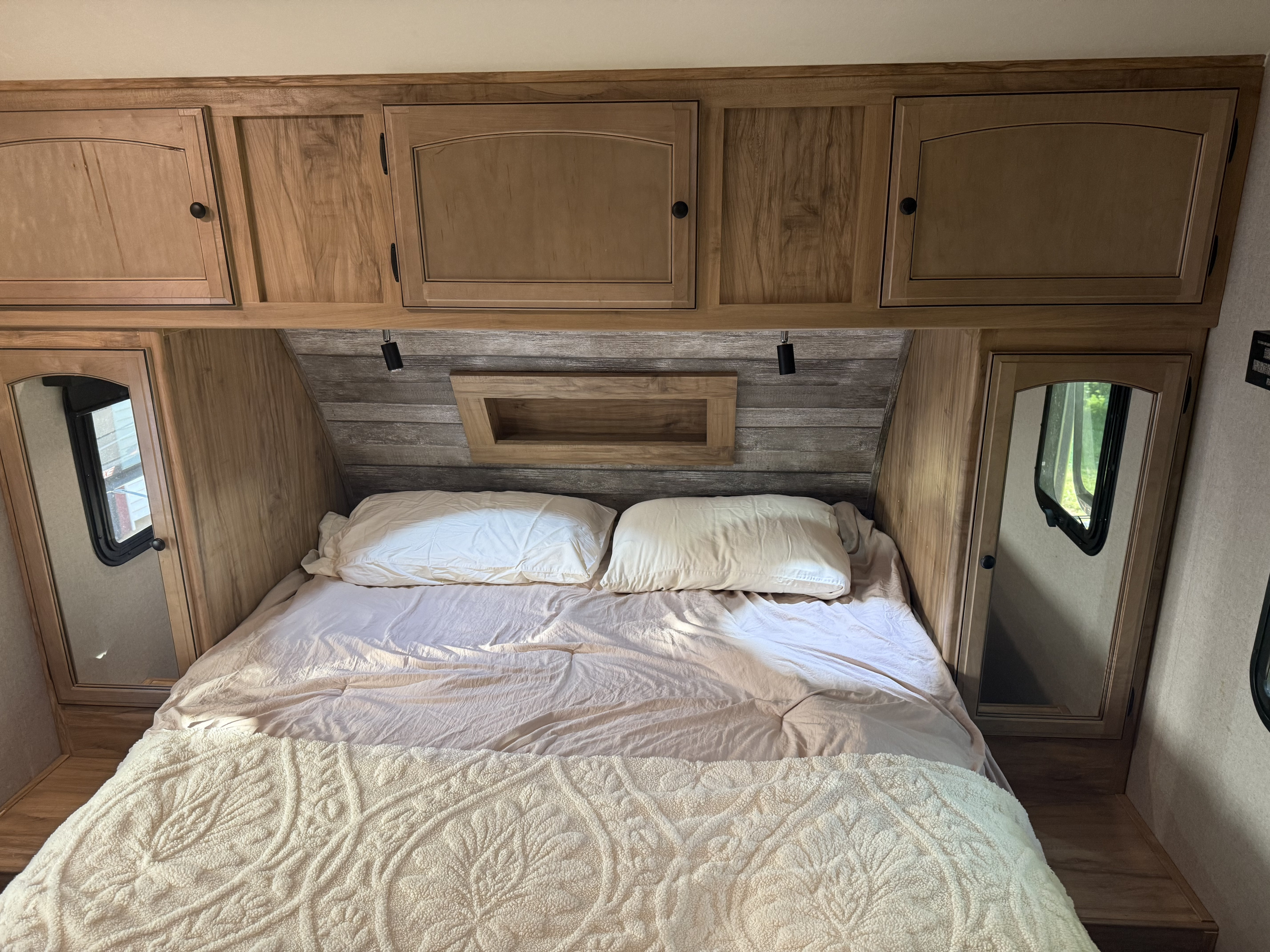 Cozy RV rental bedroom with wooden cabinets, mirror, and a comfortable bed. Ideal for your next adventure!. Coachmen Freedom Express Ultra Lite Maple Leaf Edition 2019