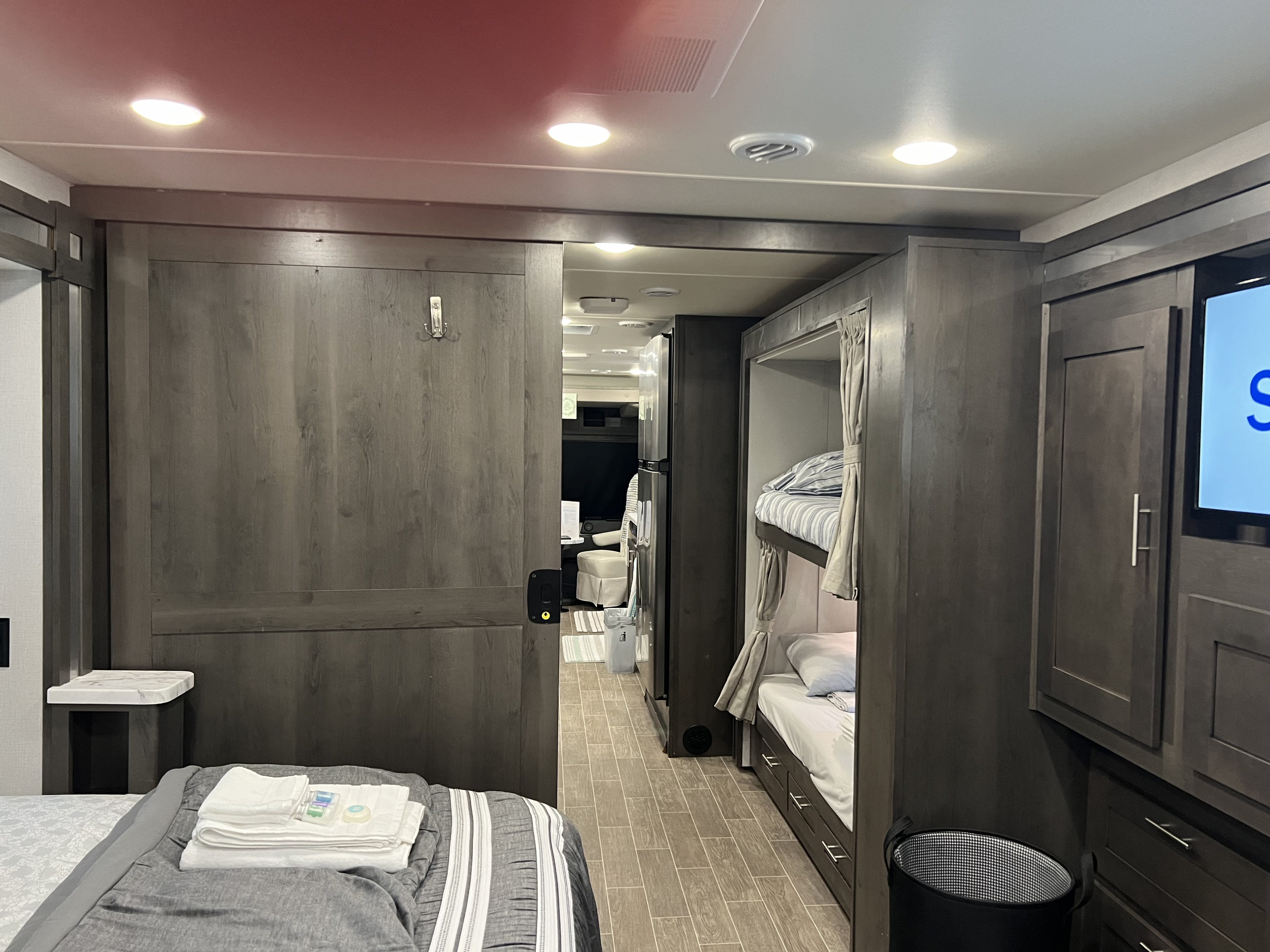 Cozy RV rental interior with a bedroom, sliding door, and bunk beds, featuring modern dark wood finishes.. Georgetown GT5 2022