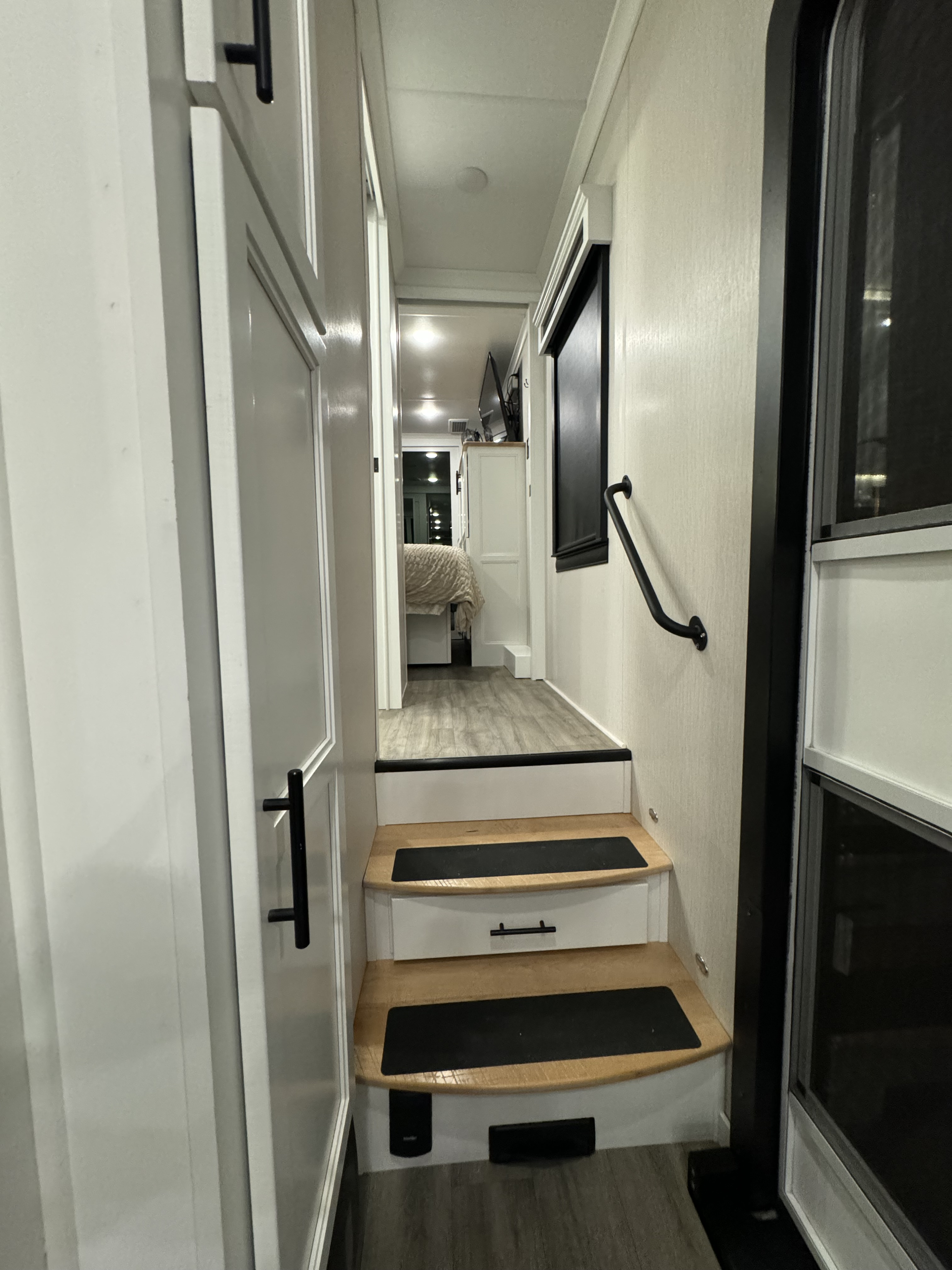 Explore this RV rental's modern interior: compact steps, hallway, and a glimpse into the master bedroom.. Riverstone Reserve 2022