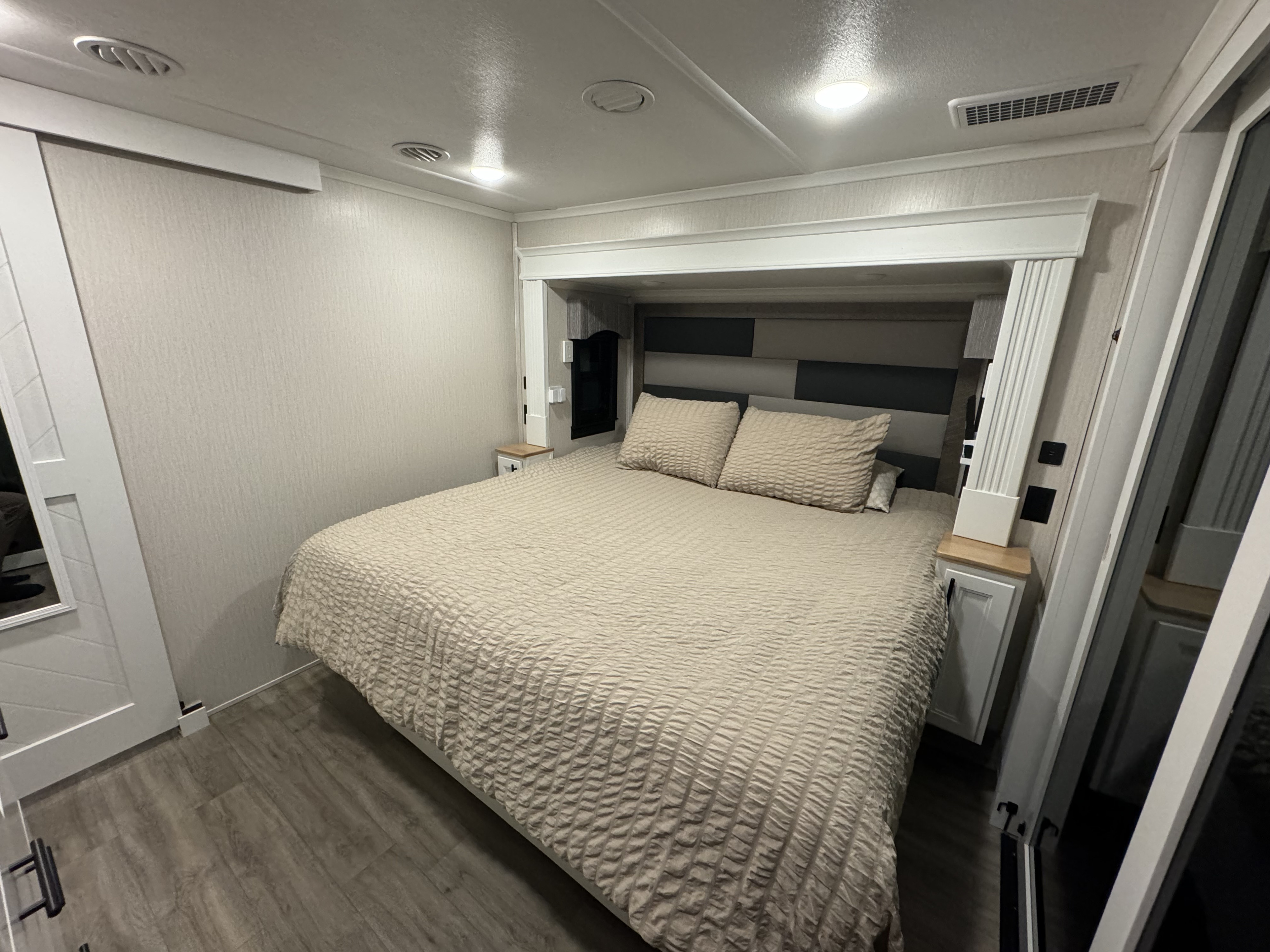 Experience a relaxing RV rental stay in this bedroom with a large bed, textured comforter, and built-in nightstands.. Riverstone Reserve 2022