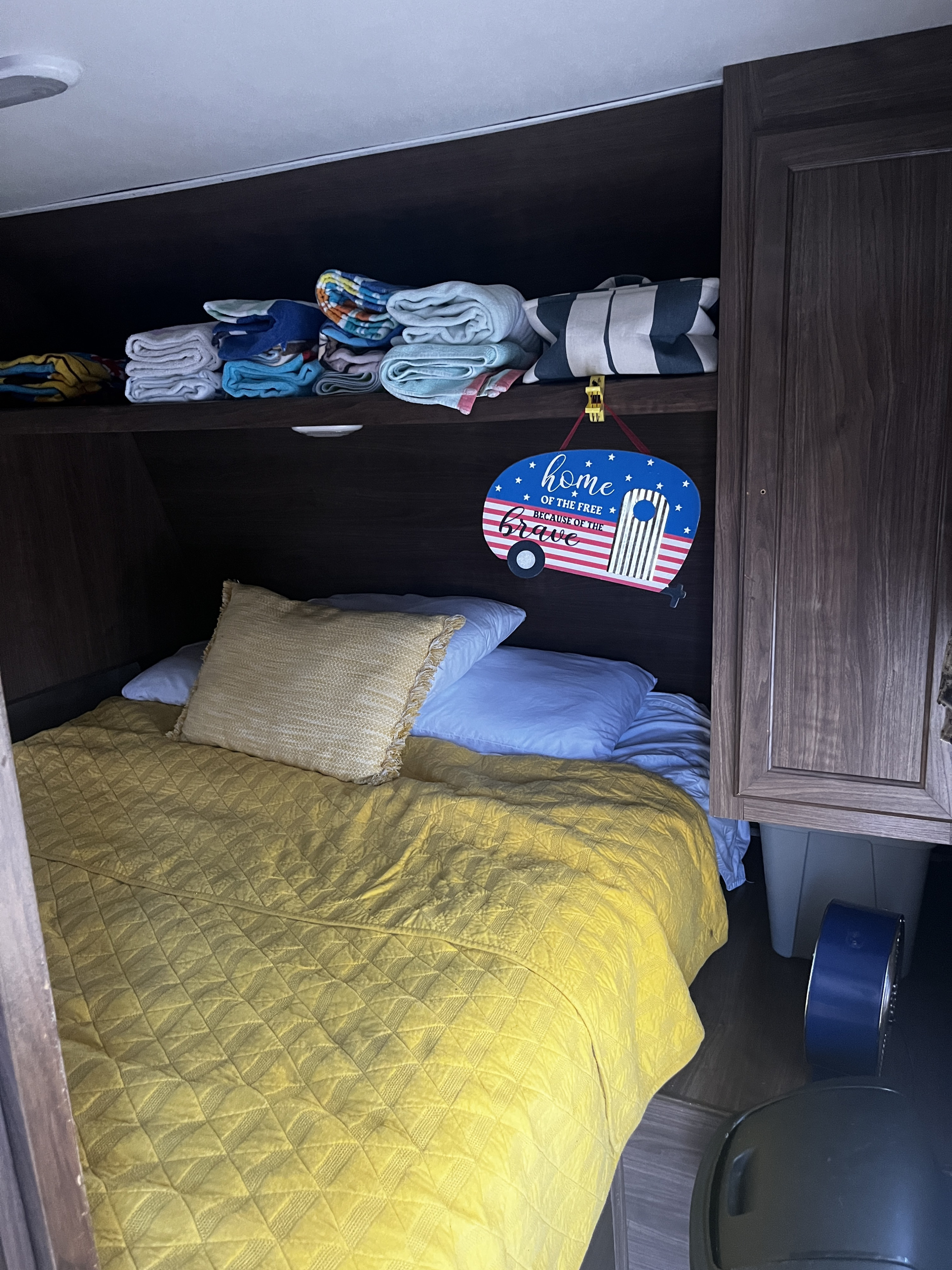 Cozy RV rental bunk: bright yellow bedding, organized overhead storage, and patriotic camper sign.. Heartland RVs Prowler Lynx 2017