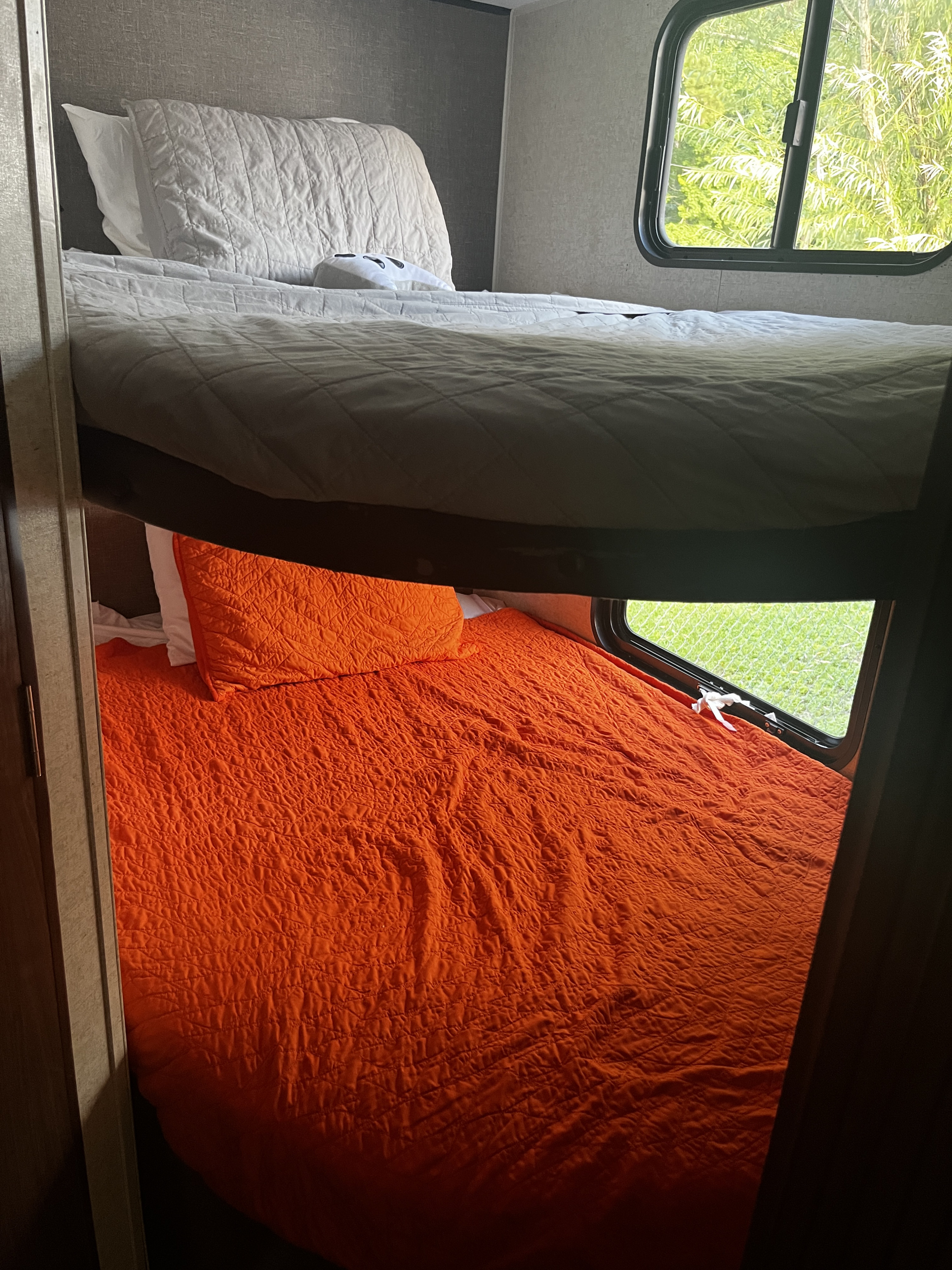 RV rental with stacked bunk beds: upper has white bedding, lower has bright orange. Ideal for family travel.. Heartland RVs Prowler Lynx 2017