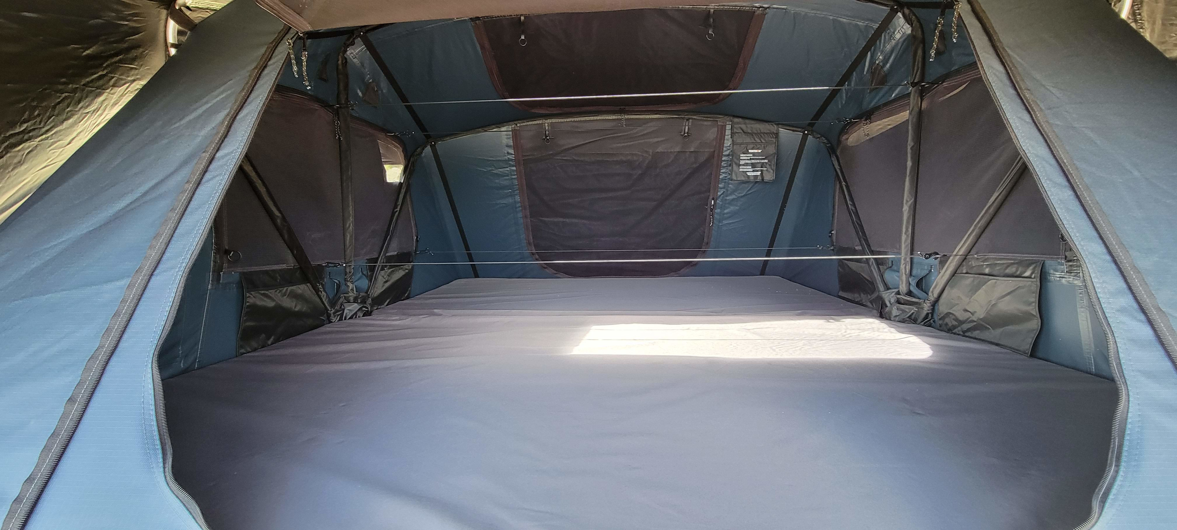 Spacious interior of a tent-style RV rental, showing a large mattress sleeping area with integrated storage. Ideal for camping.. Custom Grunt 2025