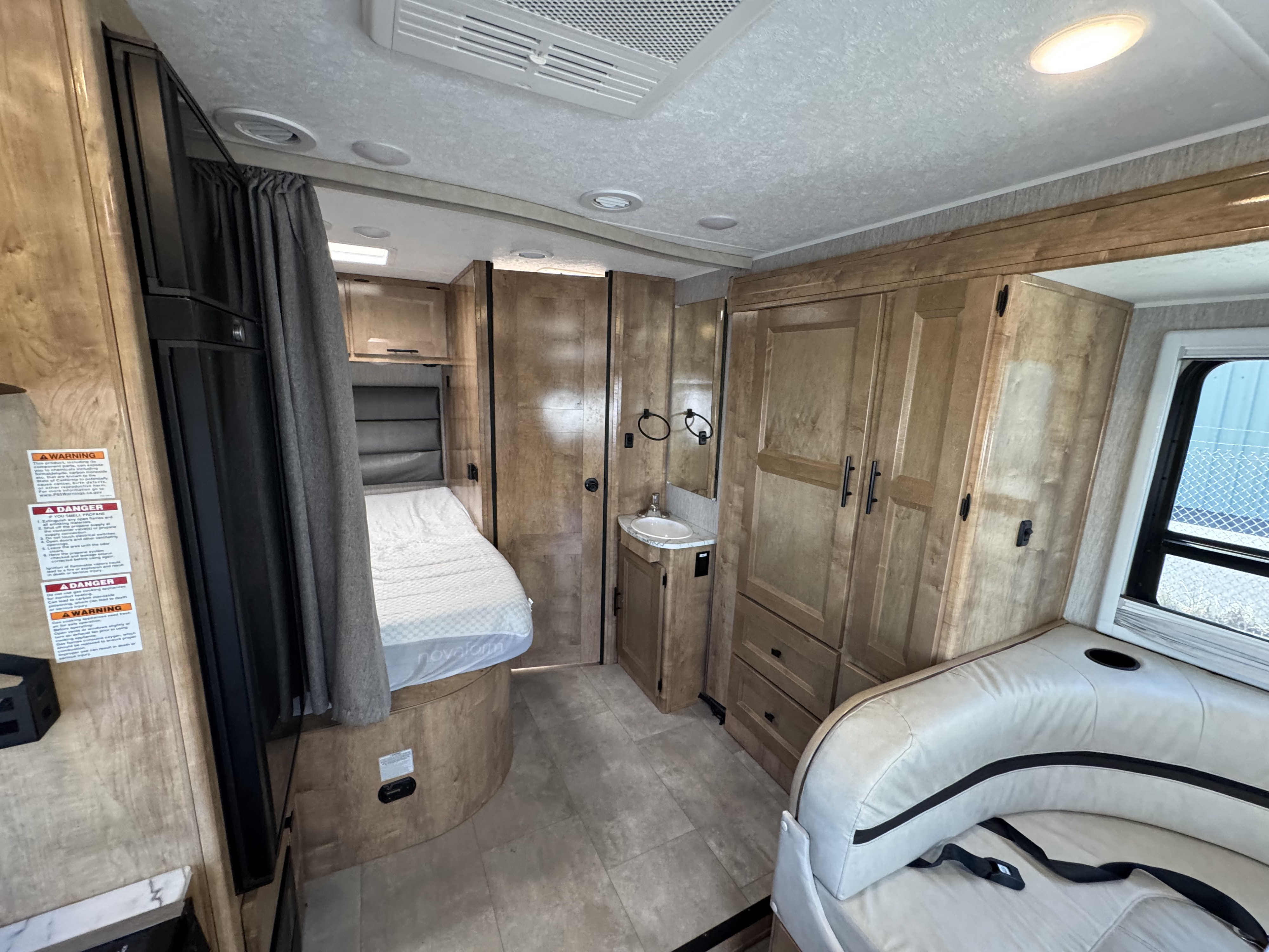 RV rental interior showing a cozy bed, compact bath area, seating, and ample storage cabinets.. Coachman Prism Select 24 CB 2021