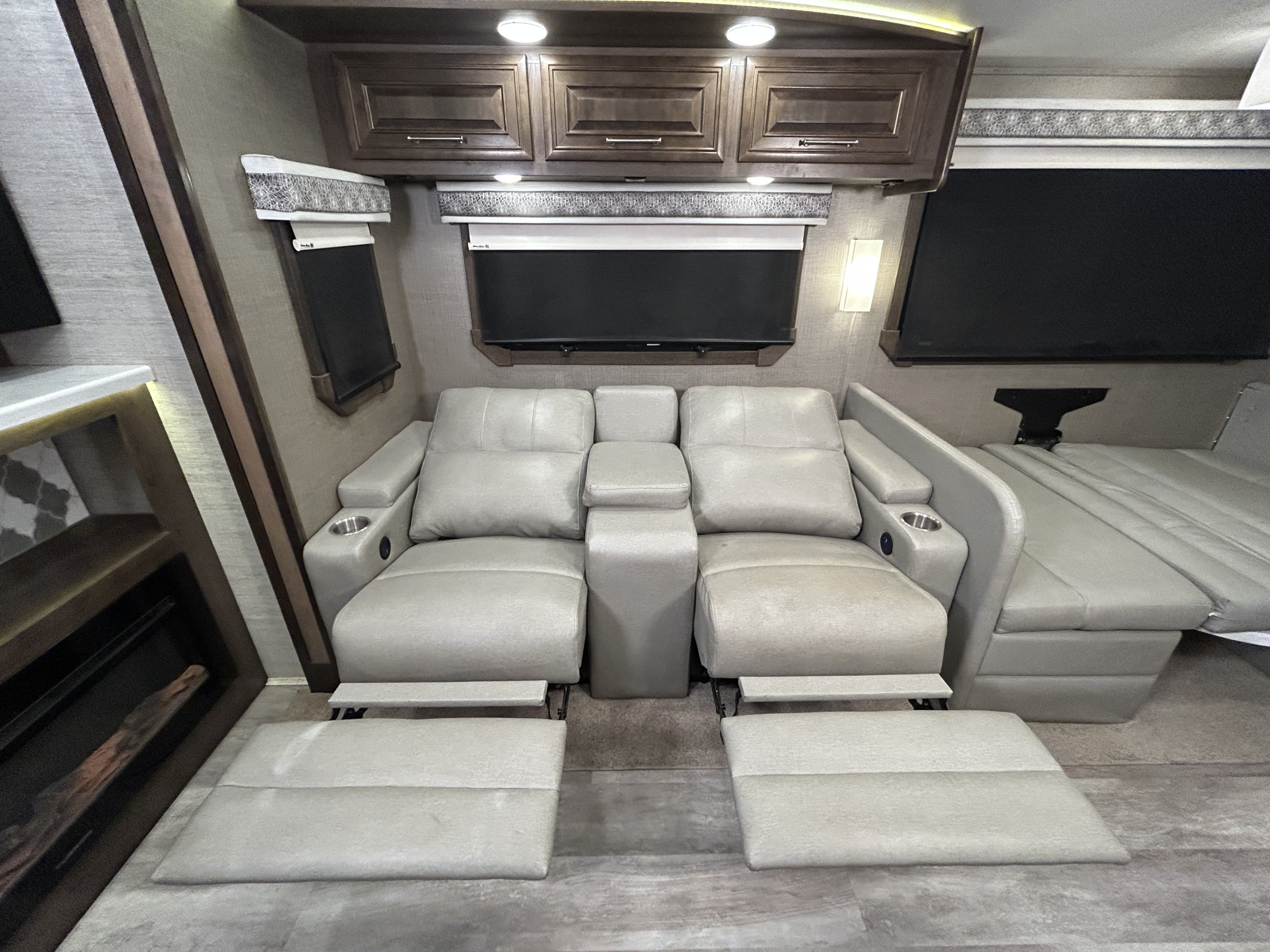 This inviting RV rental interior features comfortable light grey reclining seats, a dinette, and overhead cabinets.. Entegra Coach Accolade XL 2022