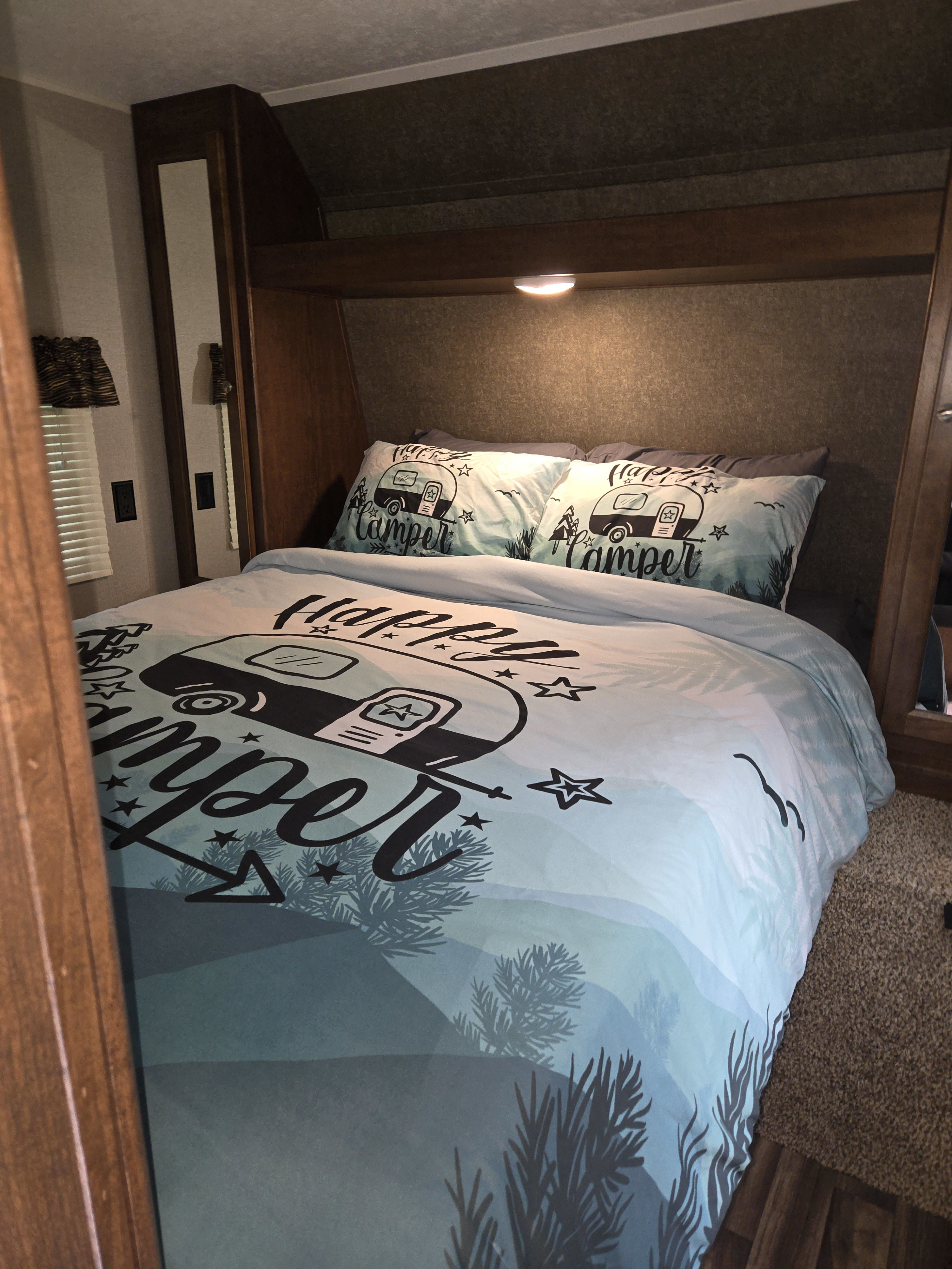 Cozy RV rental bedroom with "Happy Camper" bedding, ideal for comfortable travel adventures.. Keystone RV Hideout LHS 2018