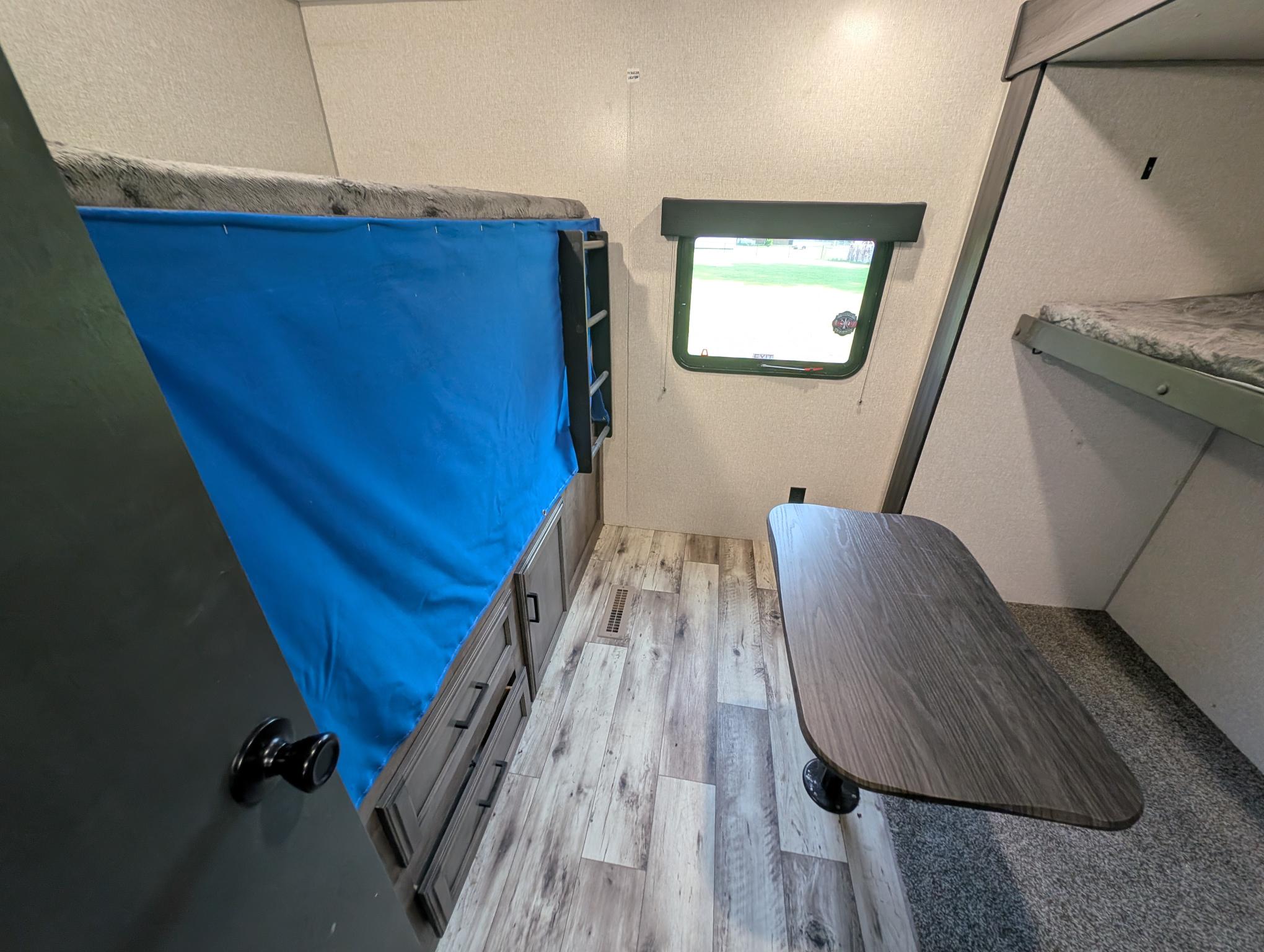 Cozy RV rental interior featuring bunk beds, a dining table, and built-in storage. Ideal for family adventures.. Venture 332VBH 2022