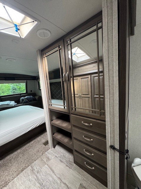 RV rental bedroom interior: spacious layout with mirrored wardrobe, dresser, bed, and skylights for a bright, comfortable stay.. Keystone RV Montana 2018