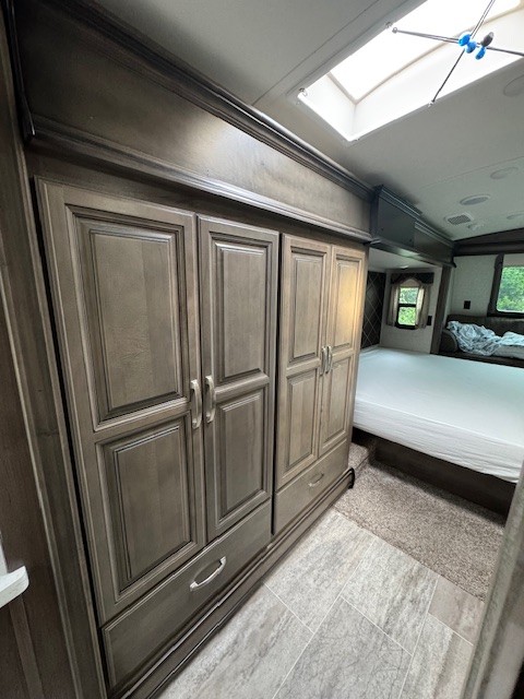 Spacious RV rental bedroom featuring a large wardrobe, comfortable bed, and bright skylight.. Keystone RV Montana 2018