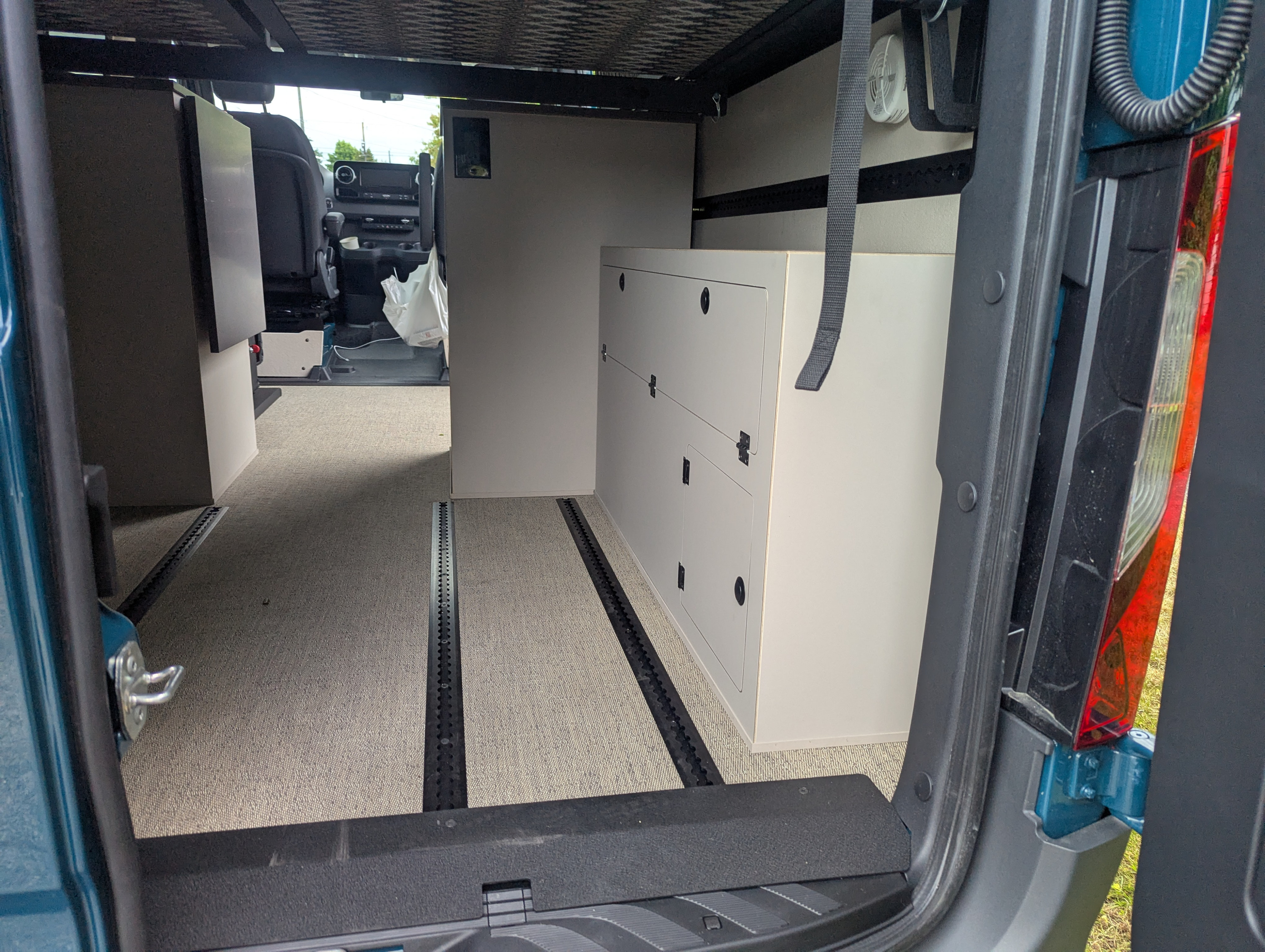 RV rental: Spacious camper van interior with modular cabinets, comfy carpet, and track flooring system.. Mercedes-Benz Sprinter 2025