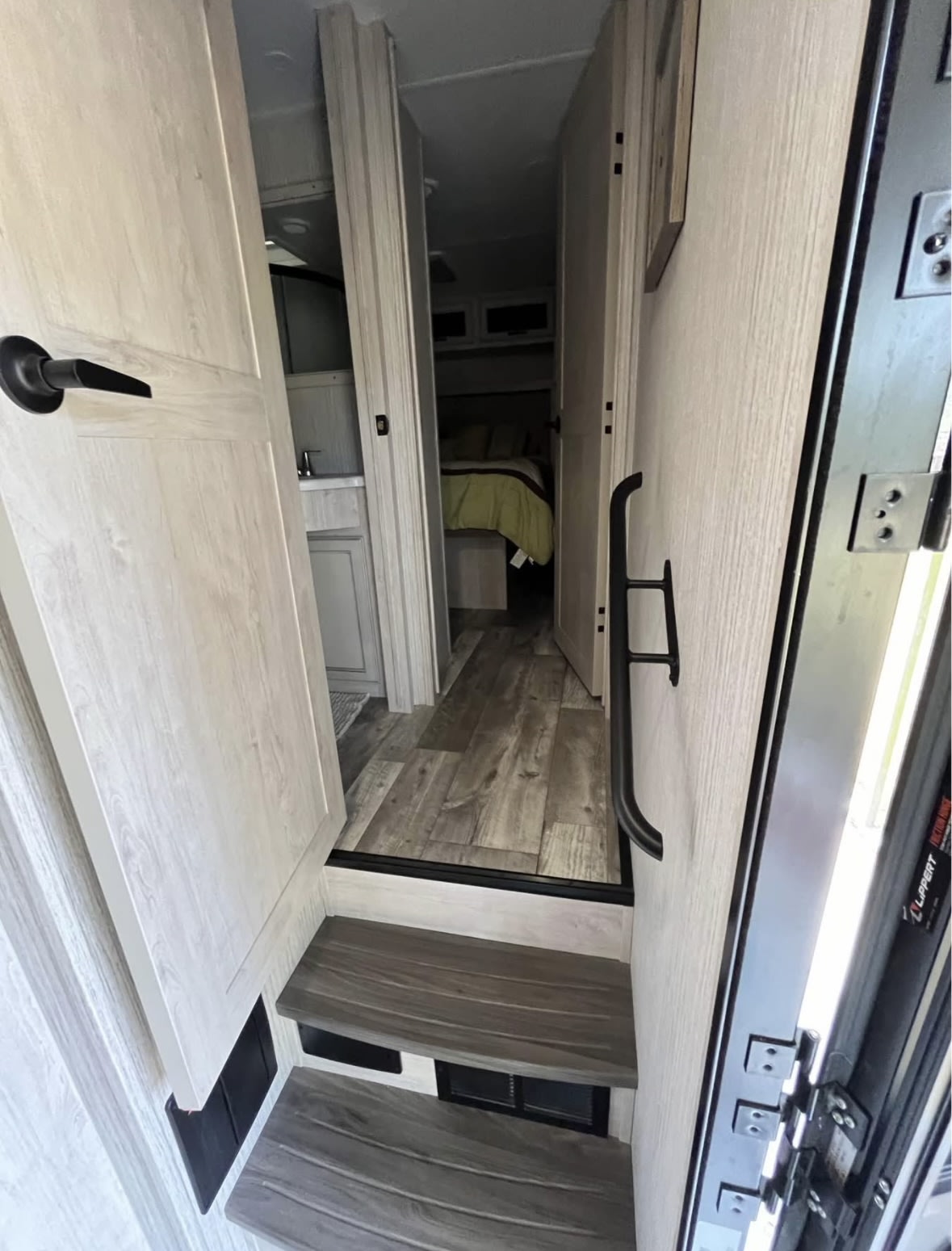 RV rental interior: Steps lead to a modern living space with a bathroom and private bedroom. Experience compact comfort!. Forest River Sierra 2023