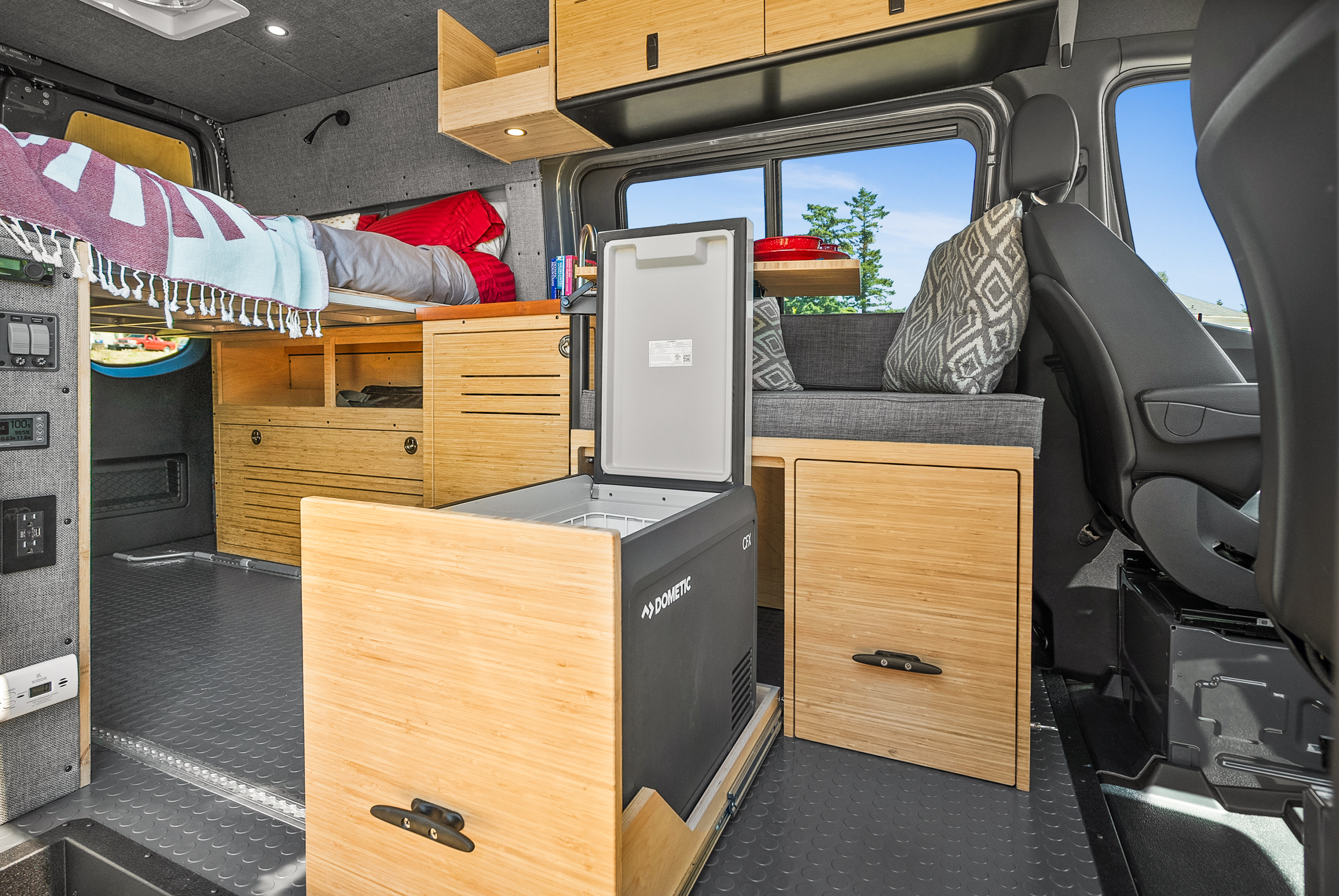 Spacious RV rental camper van interior: raised bed, bamboo storage, and a pull-out Dometic fridge.. Mercedes Sprinter 2022