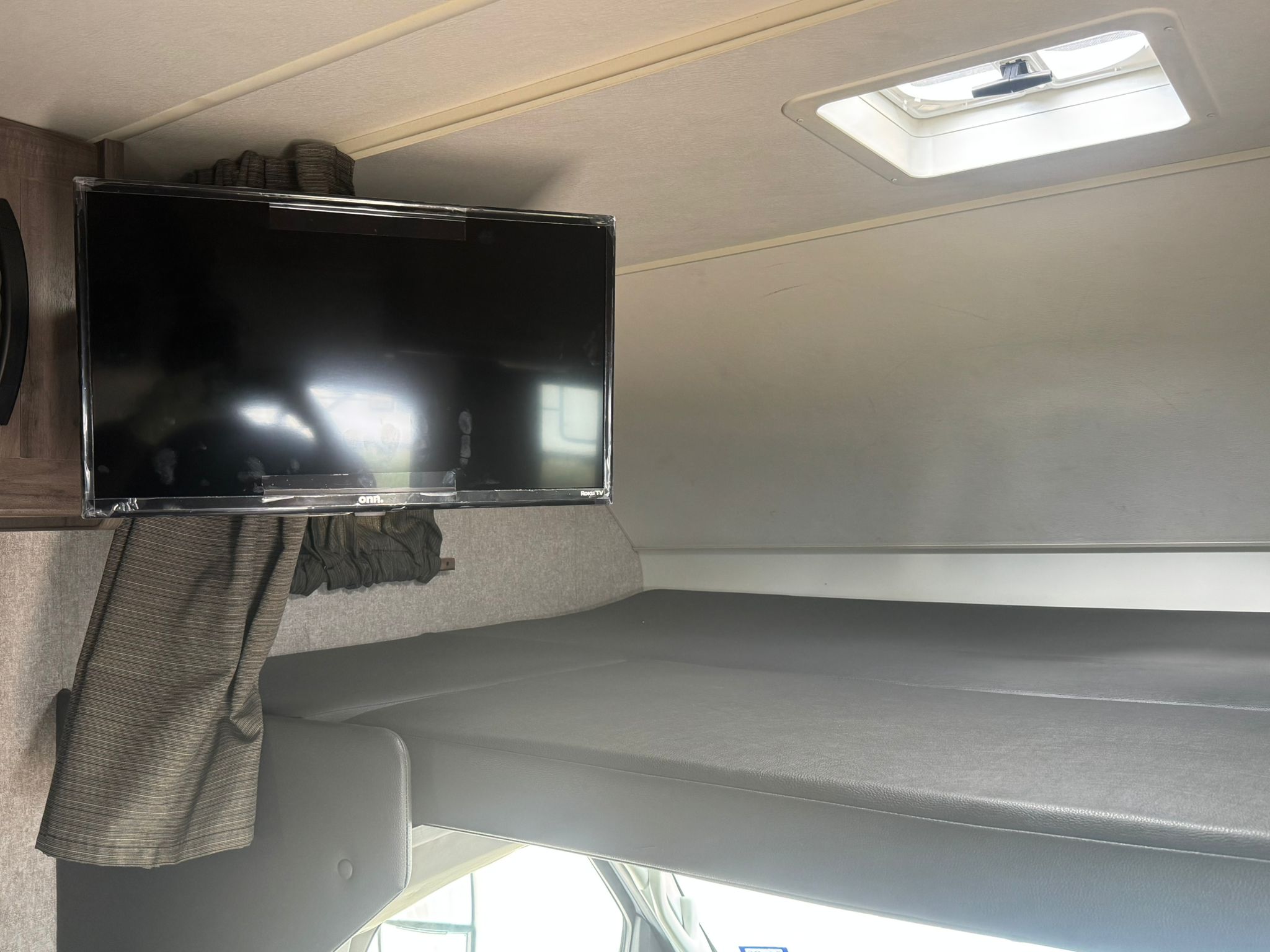 RV rental interior showing a mounted TV, overhead bunk bed, and ceiling vent. A compact, functional space.. Winnebago Minnie Winnie 2020