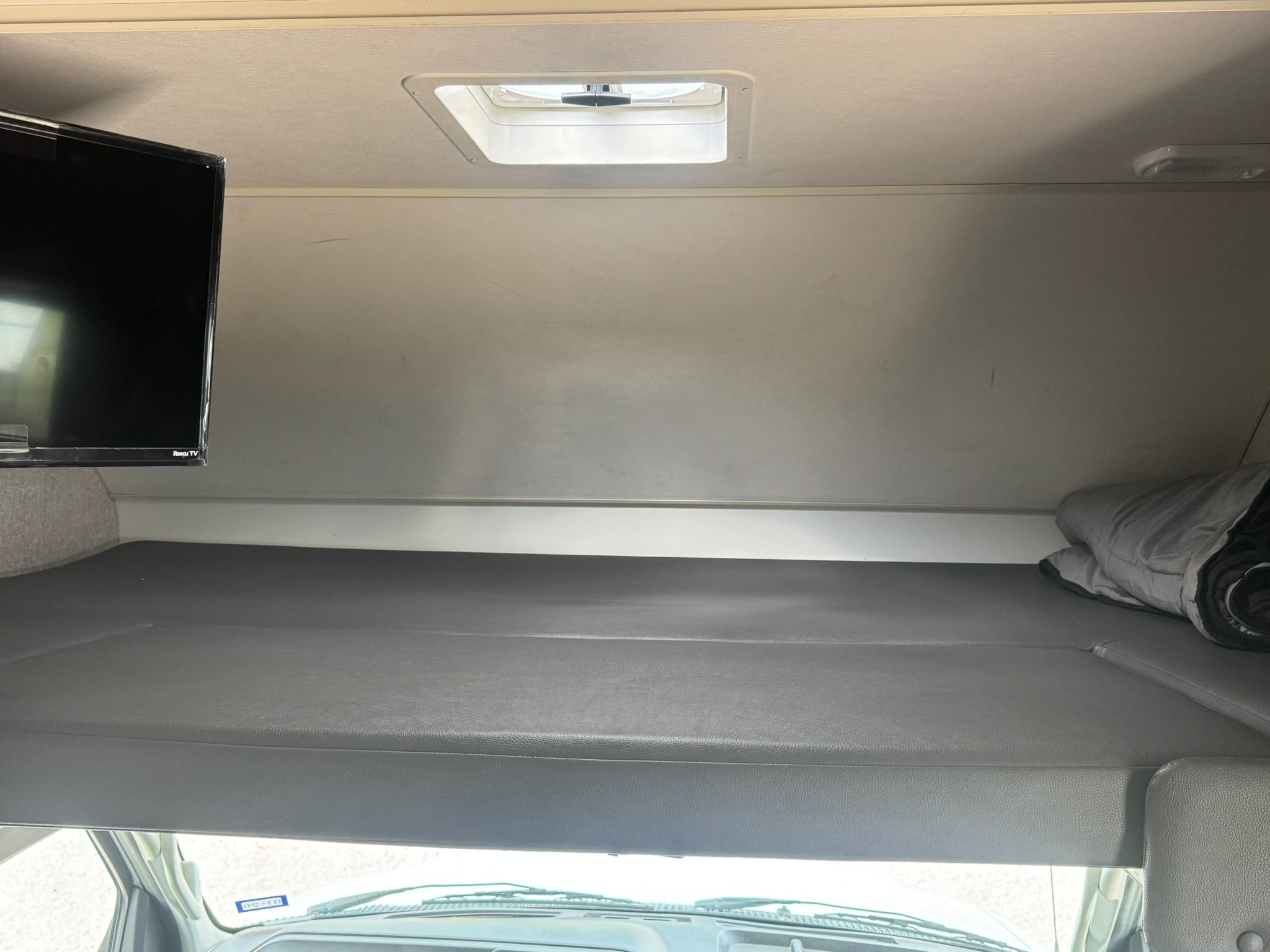 Spacious cab-over bunk bed inside an RV rental, featuring a TV and roof vent. Great for extra sleeping.. Winnebago Minnie Winnie 2020