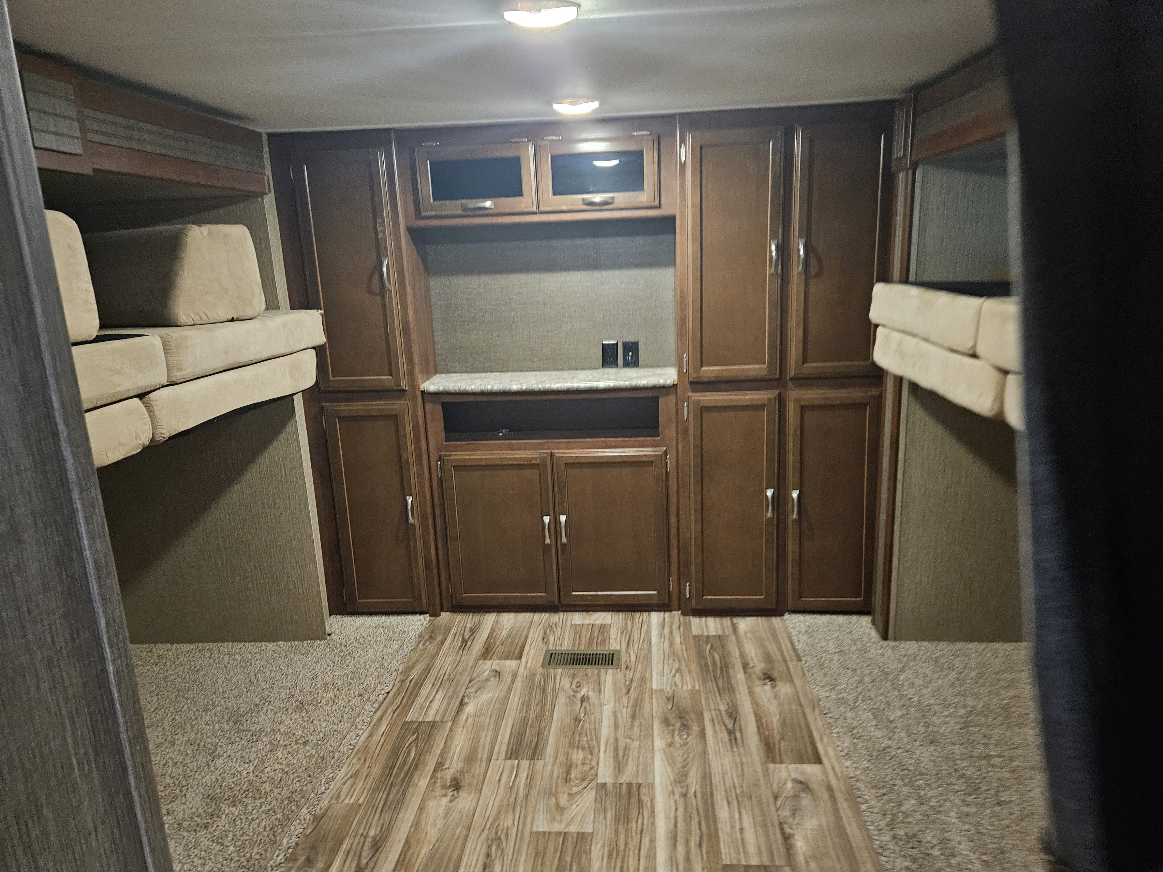 RV rental interior features bunk beds, wood cabinets with media center, and mixed carpet/wood-look flooring.. Keystone RV Passport Grand Touring 2016