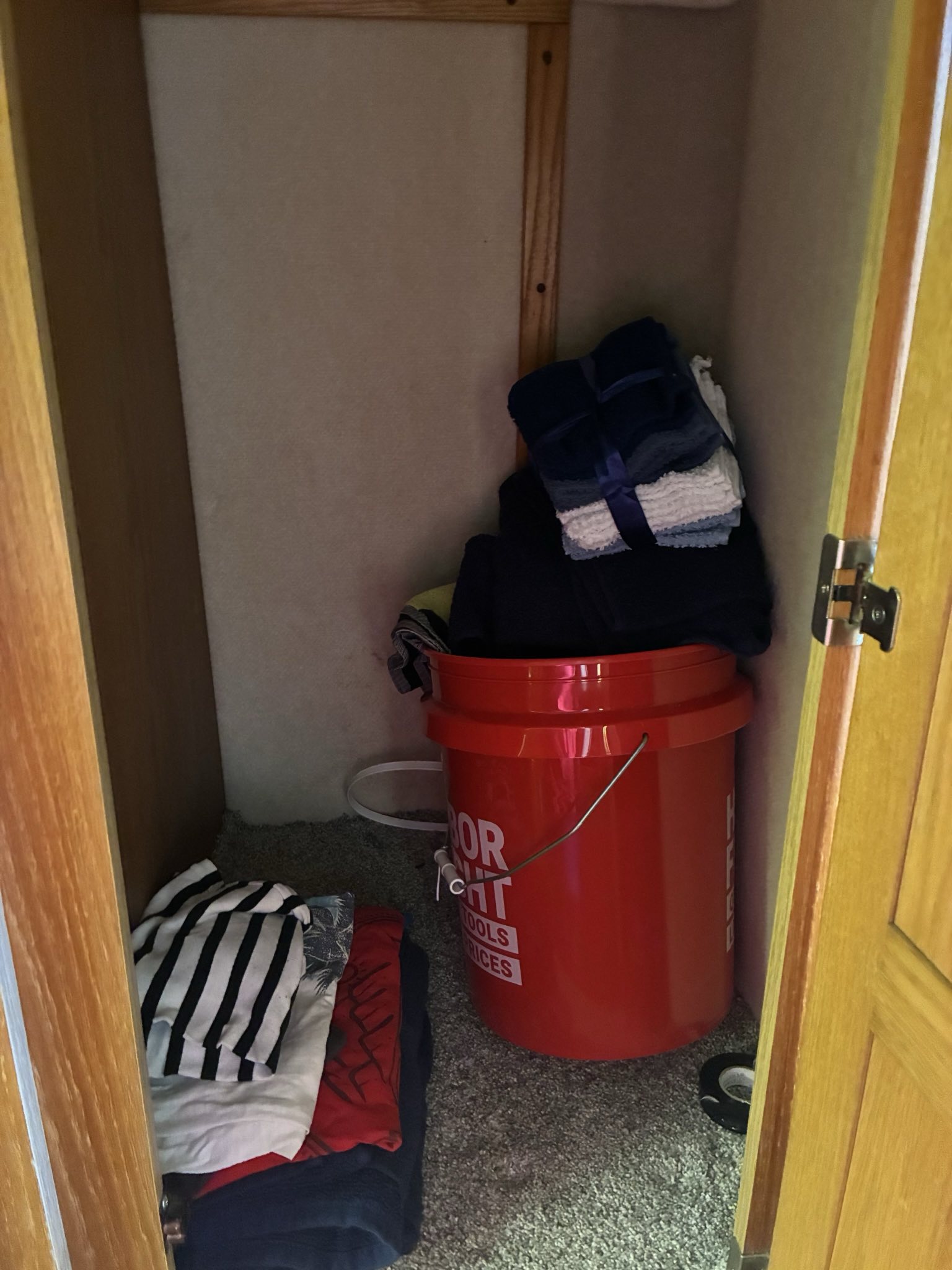 RV rental storage: neatly organized towels, clothes, and a red bucket in a compact space, useful for travel.. Born Free Born Free Motorhome 2005