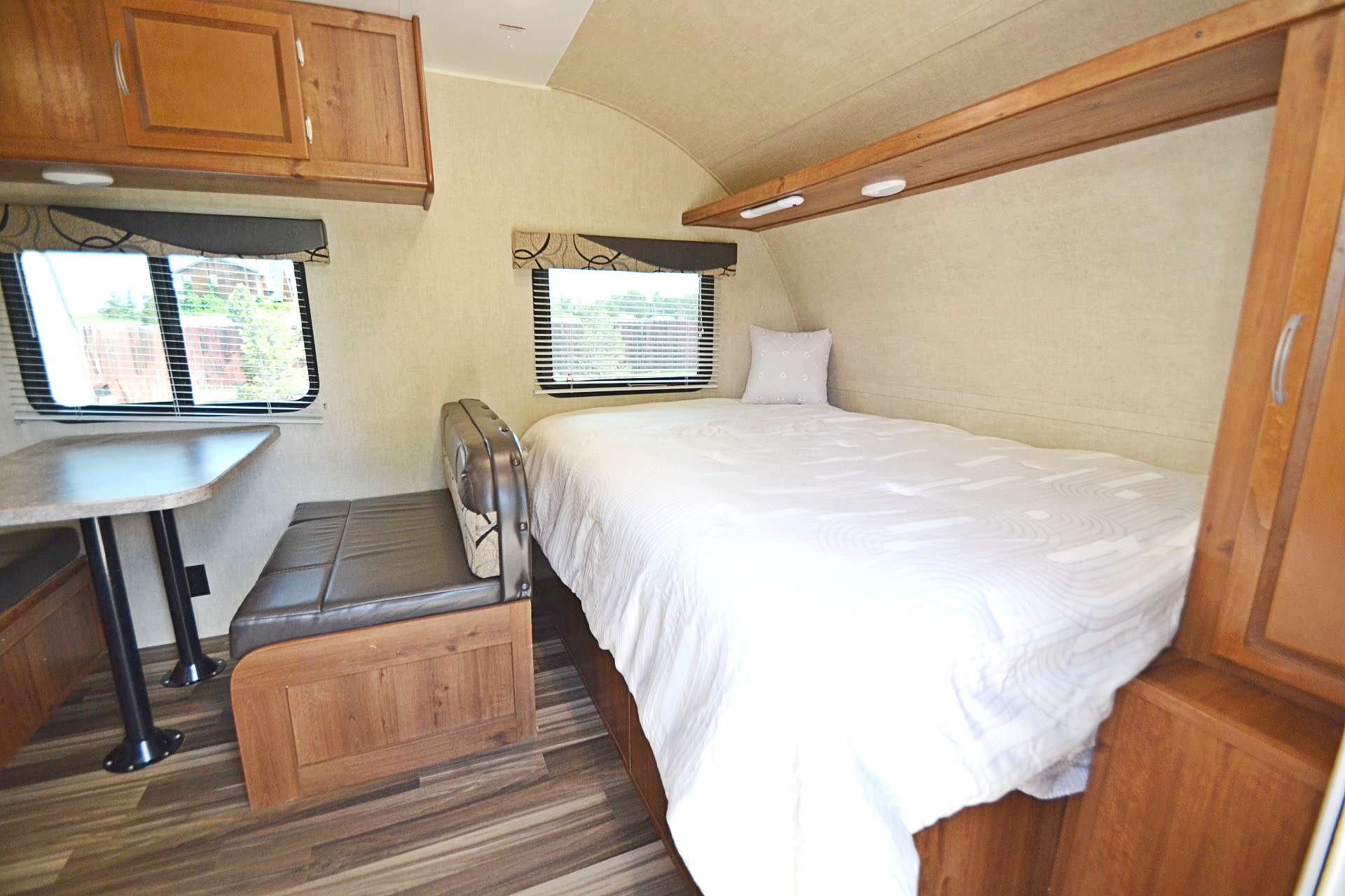 Cozy RV rental interior: a comfy bed, dinette, and wood-toned cabinetry. Ideal for your next travel trailer adventure.. Gulf Stream Ameri-Lite 2017