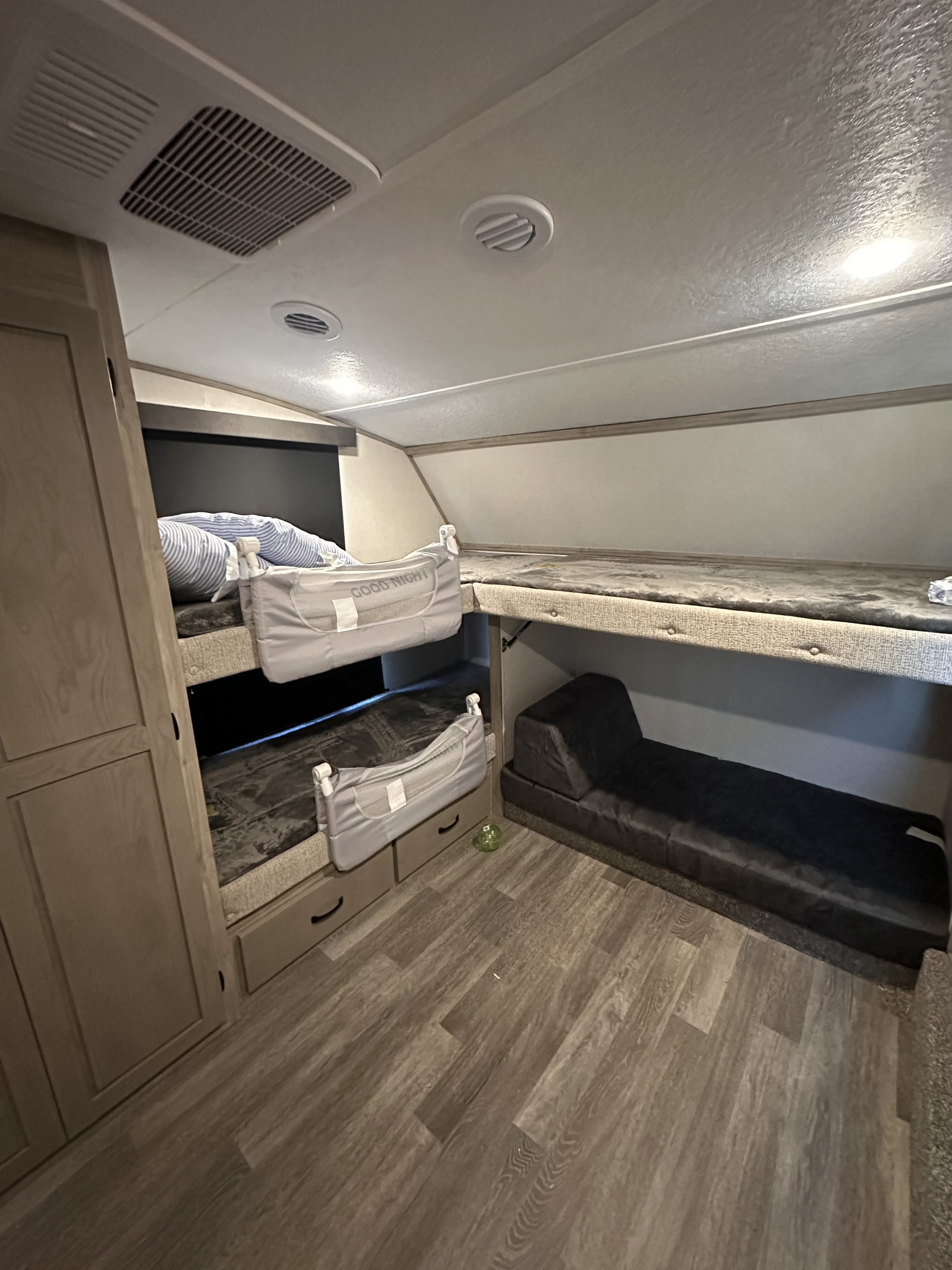 RV rental bunkhouse showing three bunk beds, a floor pad, and built-in storage. HVAC vents are visible on the ceiling.. Coachman chaparral 355 fbx 2024