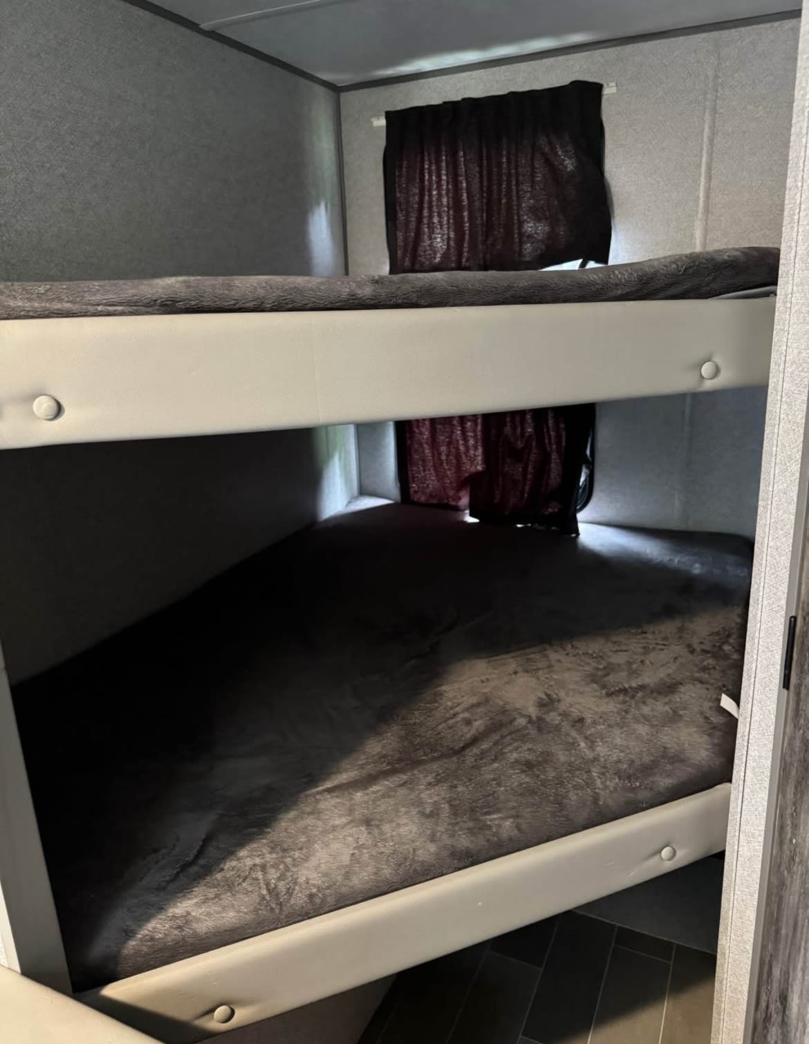 RV rental bunk beds: cozy sleeping area with grey bedding & dark curtains, ideal for compact travel.. Forest River Salem FSX 2021