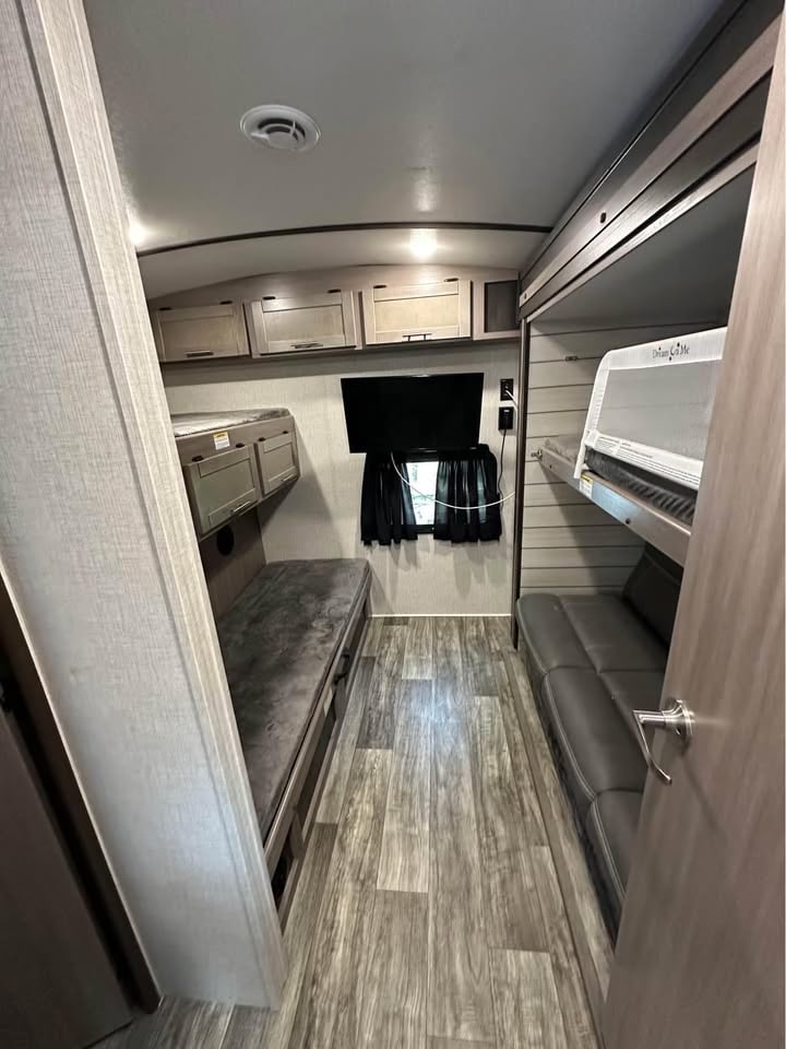 Cozy rv rental interior with bunk beds, convertible sofa, TV, and overhead cabinets for a compact sleeping area.. Crossroads RV Sunset Trail Super Lite 2021