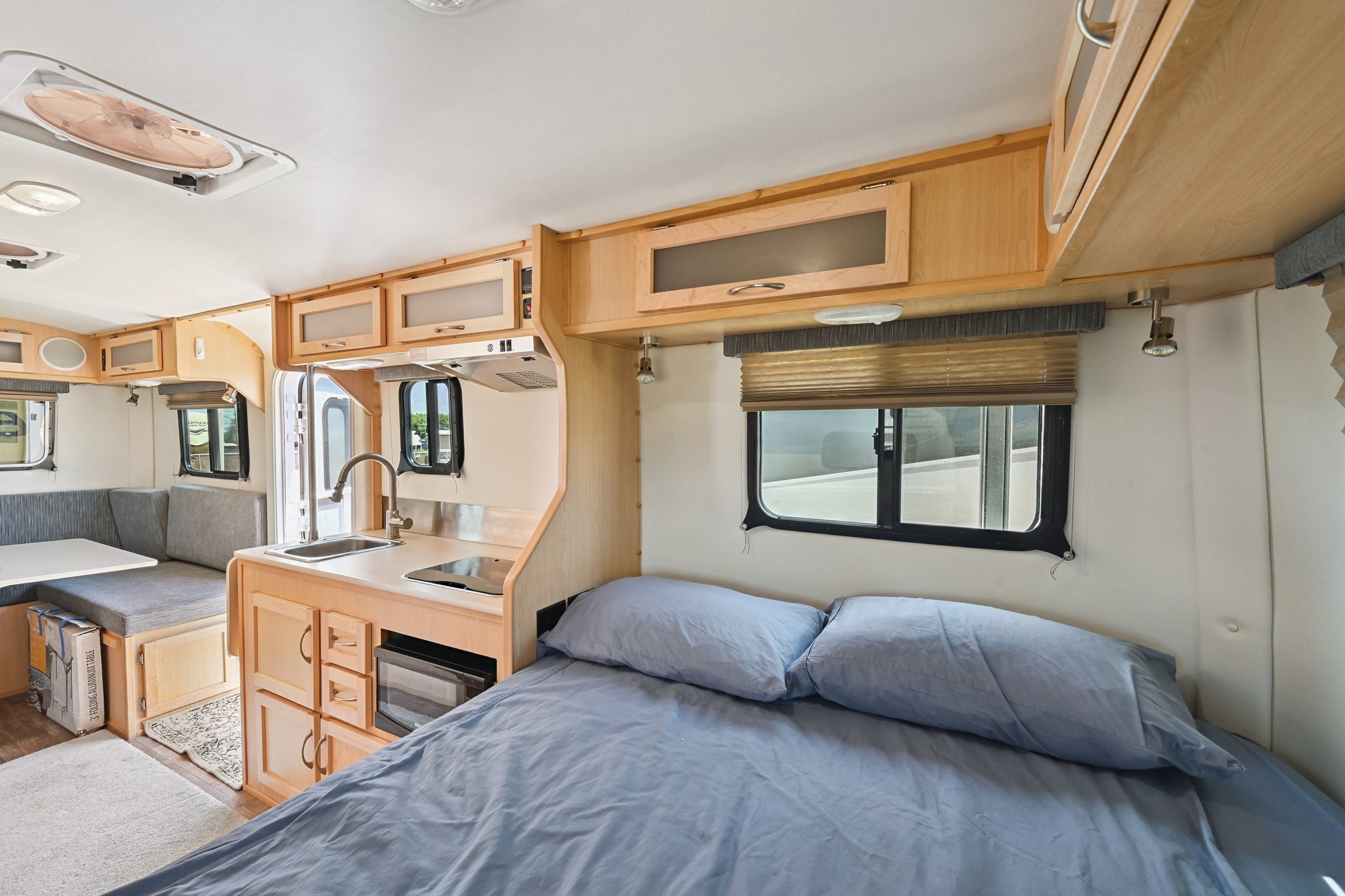 Cozy RV rental interior featuring a bed, compact kitchen, and dining area, perfect for comfortable travel.. Escape Trailer Escape Trailer Trailer 2021