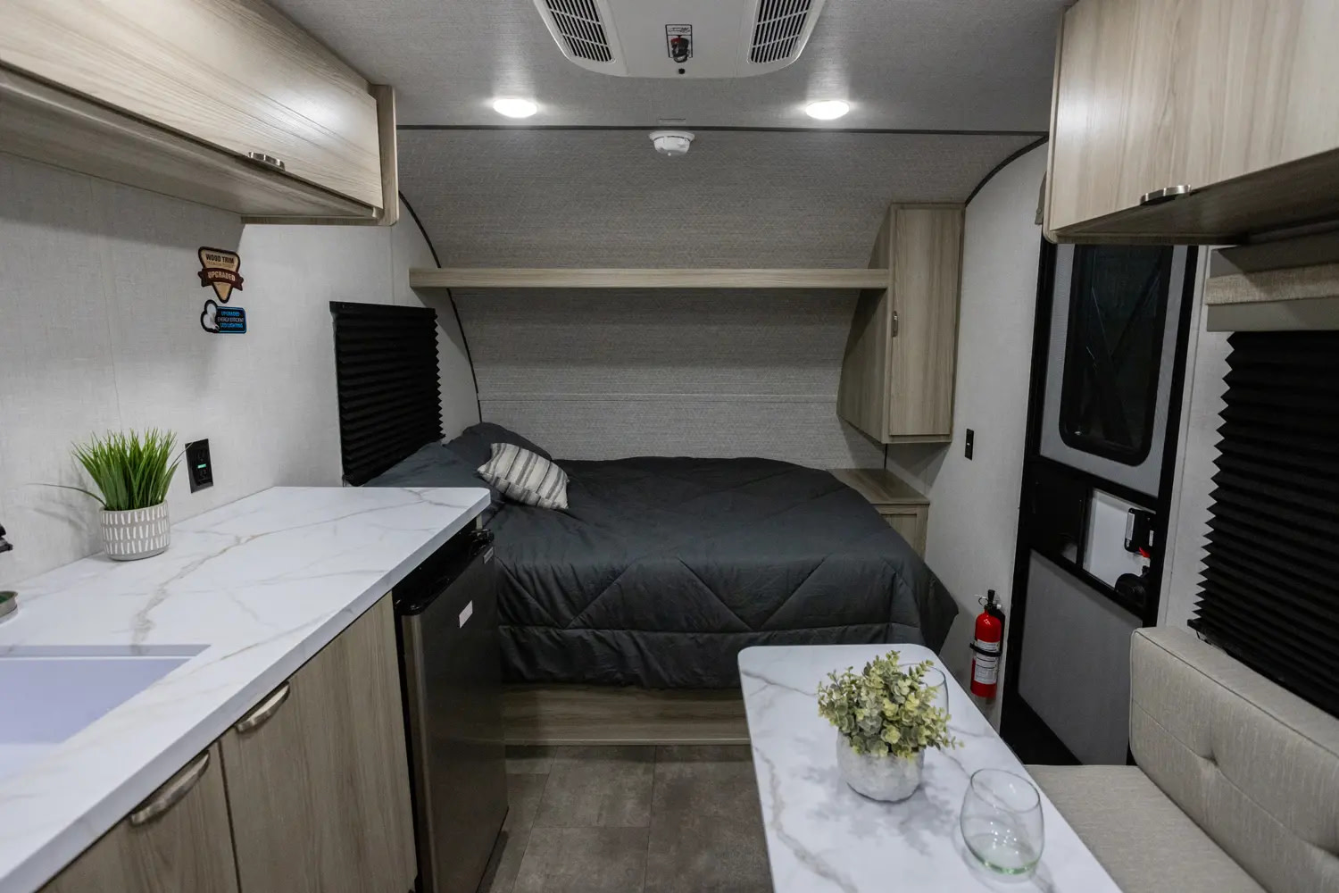 RV rental interior features a cozy bed, compact kitchen, and dinette. Ideal for travel trailer adventures.. Wildwood TT174DBH 2025