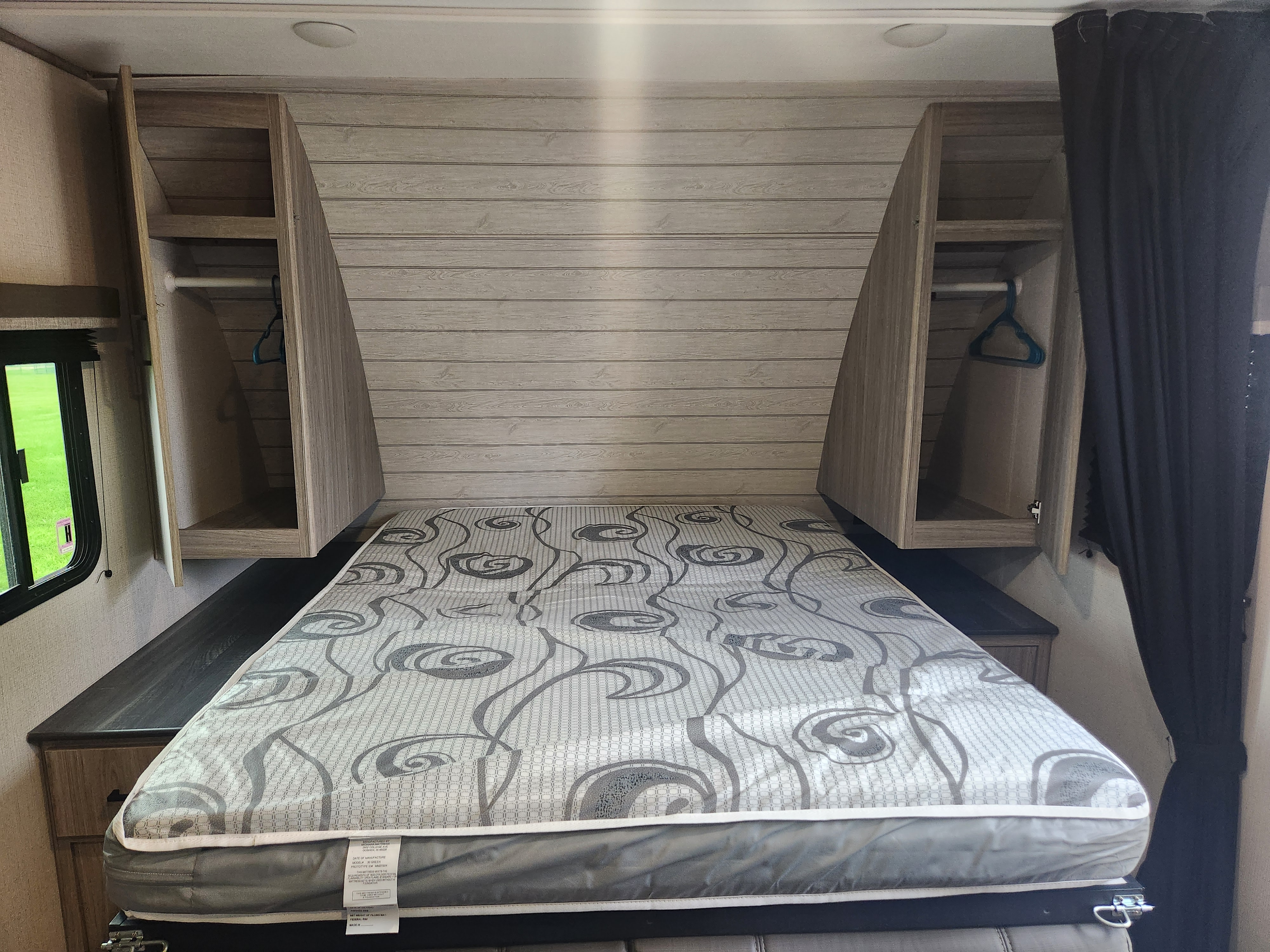 RV rental bedroom: a compact space with a patterned mattress, built-in storage, and a side window.. Keystone RV Passport SL 2022