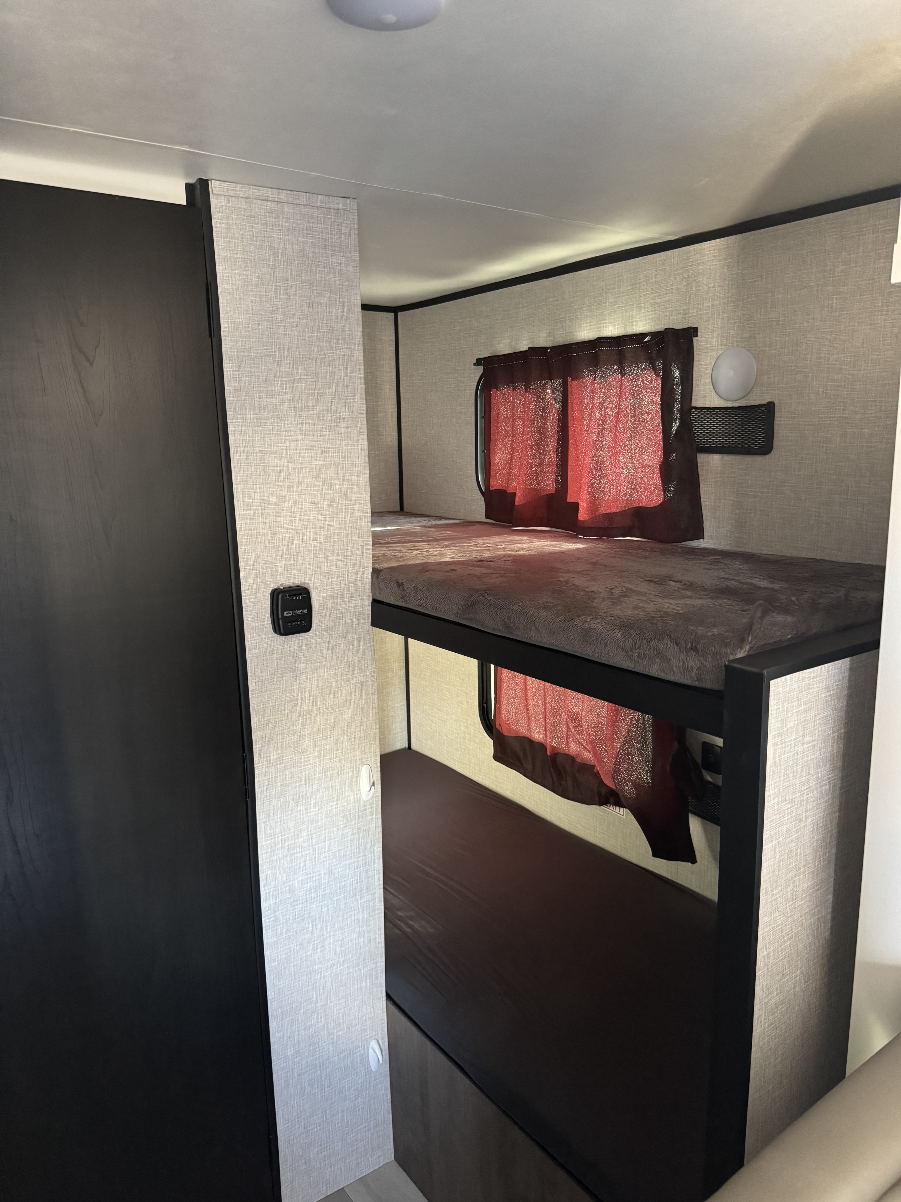 RV rental: Interior of a camper showing cozy stacked bunk beds, dark curtains, and a thermostat.. 58TBM0AK1S75M3067 180bhs 2025